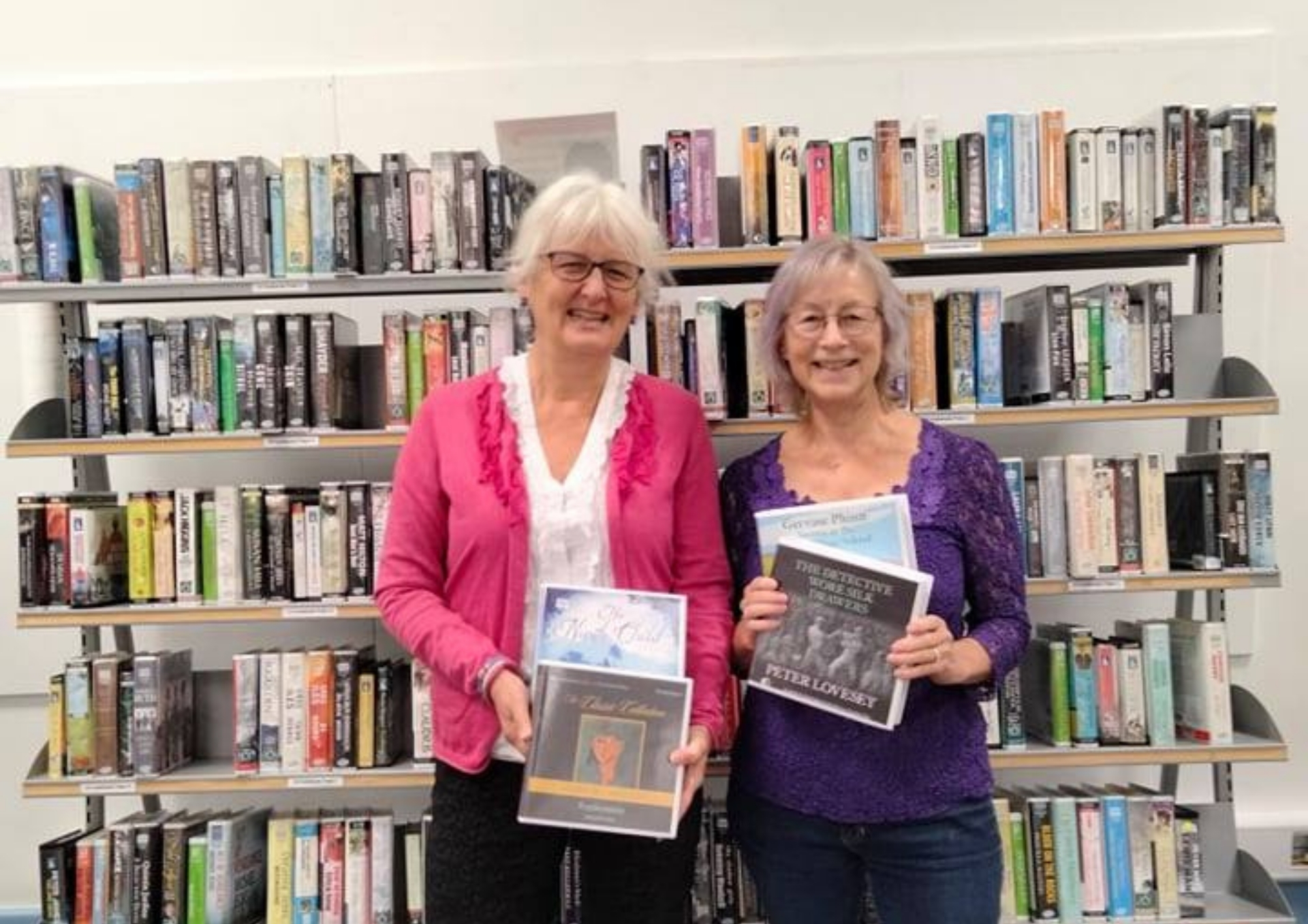 A photo showing Hilary Cox (Libraries and Information Service) and Caroline Talbott (Jean's daughter) in front of a library shelf of audio books