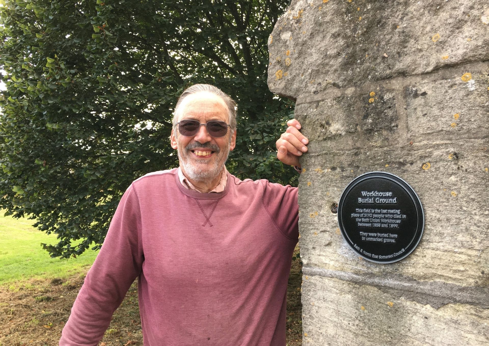 John Payne standing next to plaque marking burial ground
