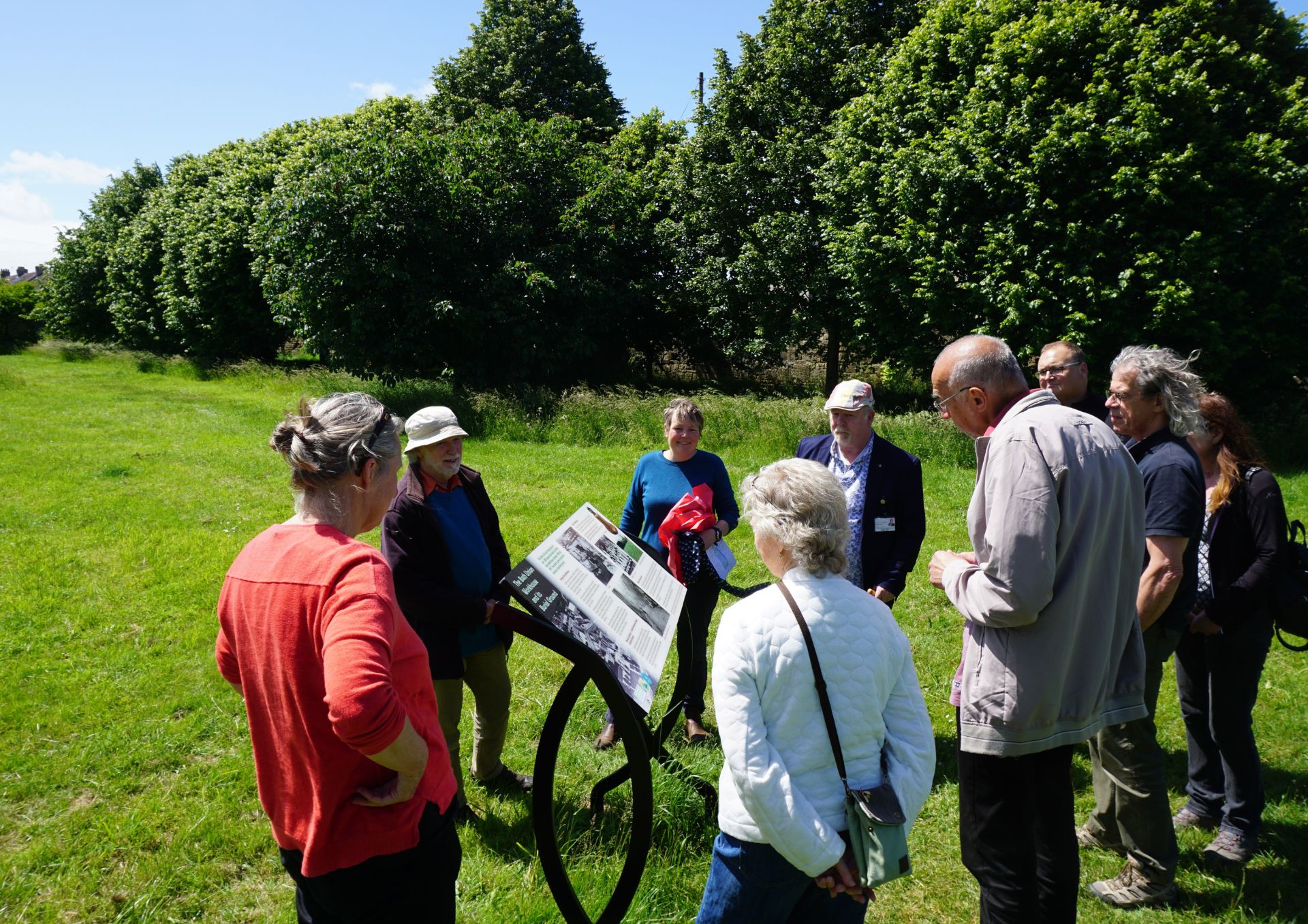 A photo showing the information board in it's outdoor setting and attendees at the unveiling