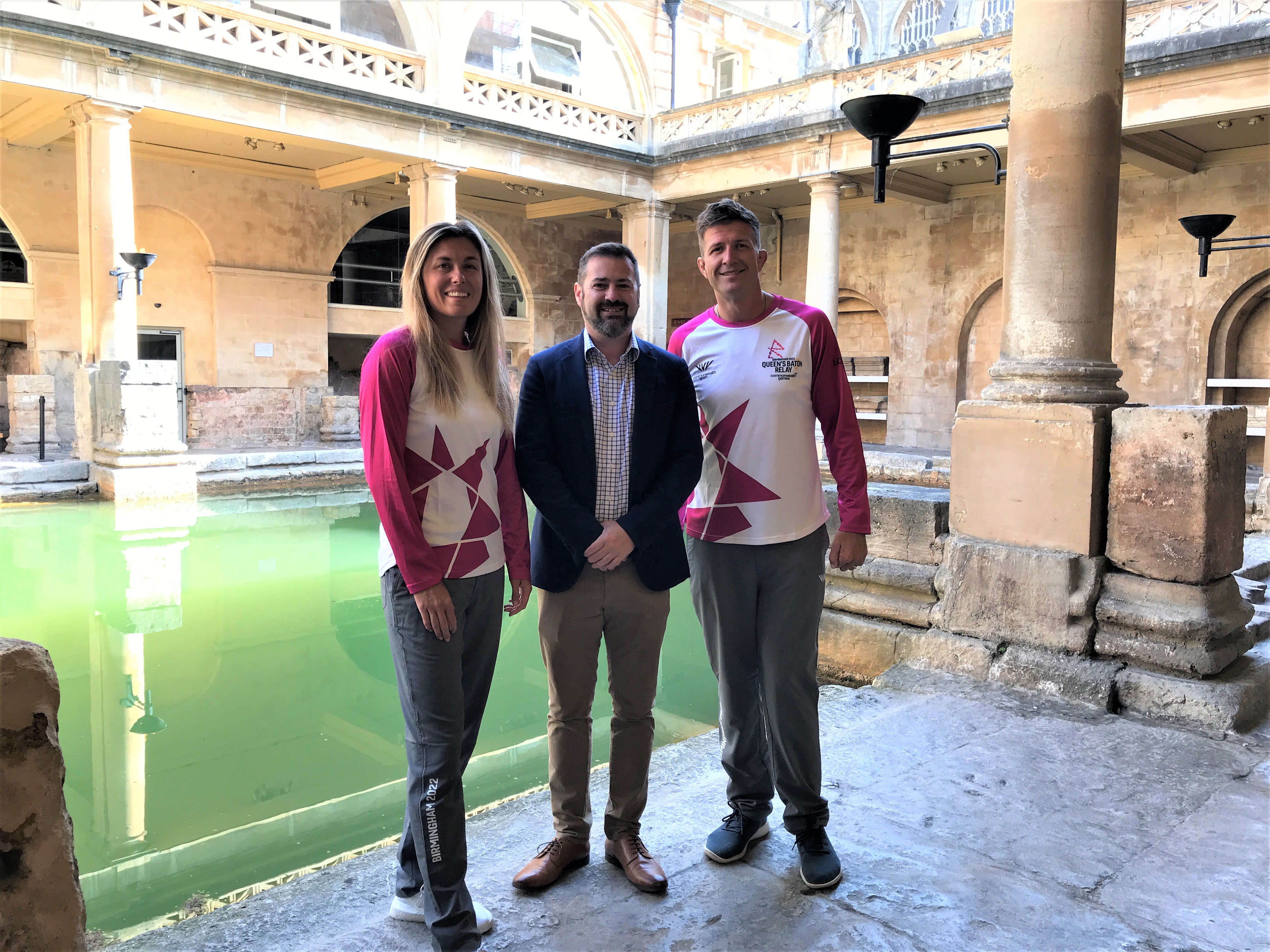 Batonbearers Lois and Ed Jackson with Councillor Kevin Guy by the Great Bath at the Roman Baths