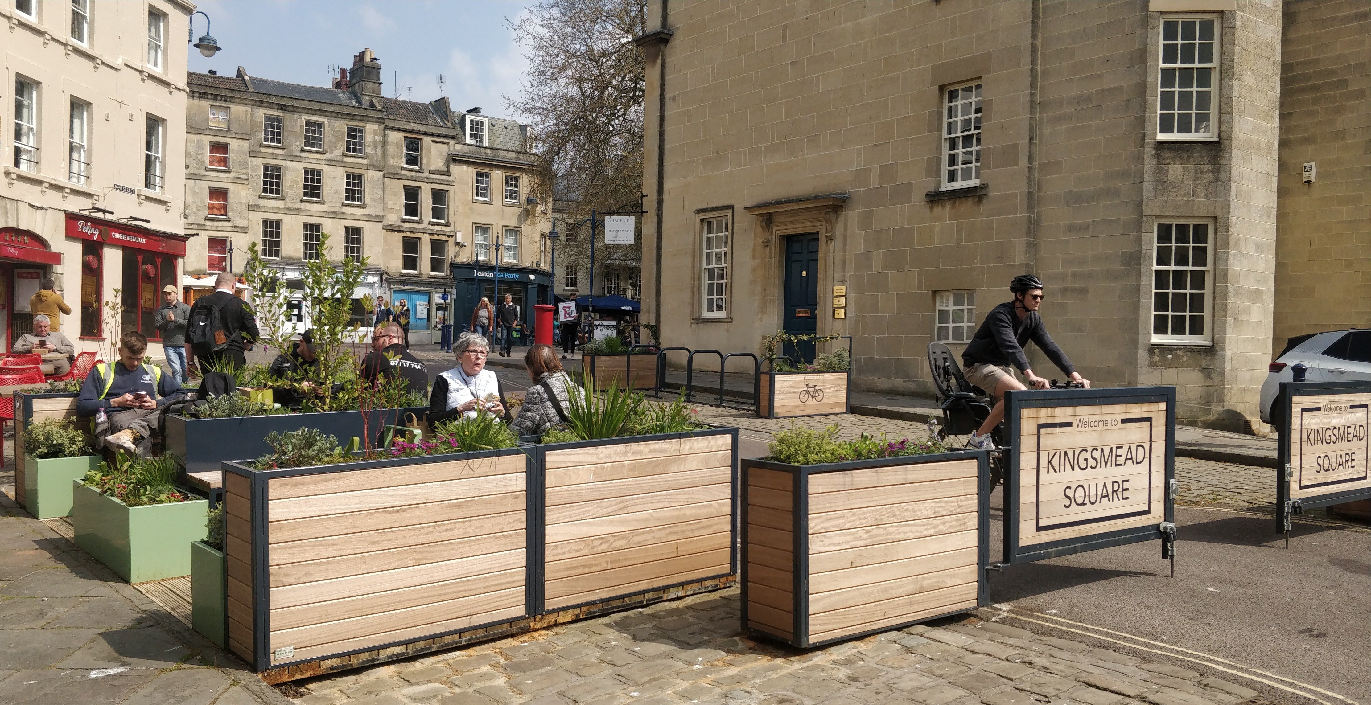 gateway into kingsmead square showing people using the seating and cycling through