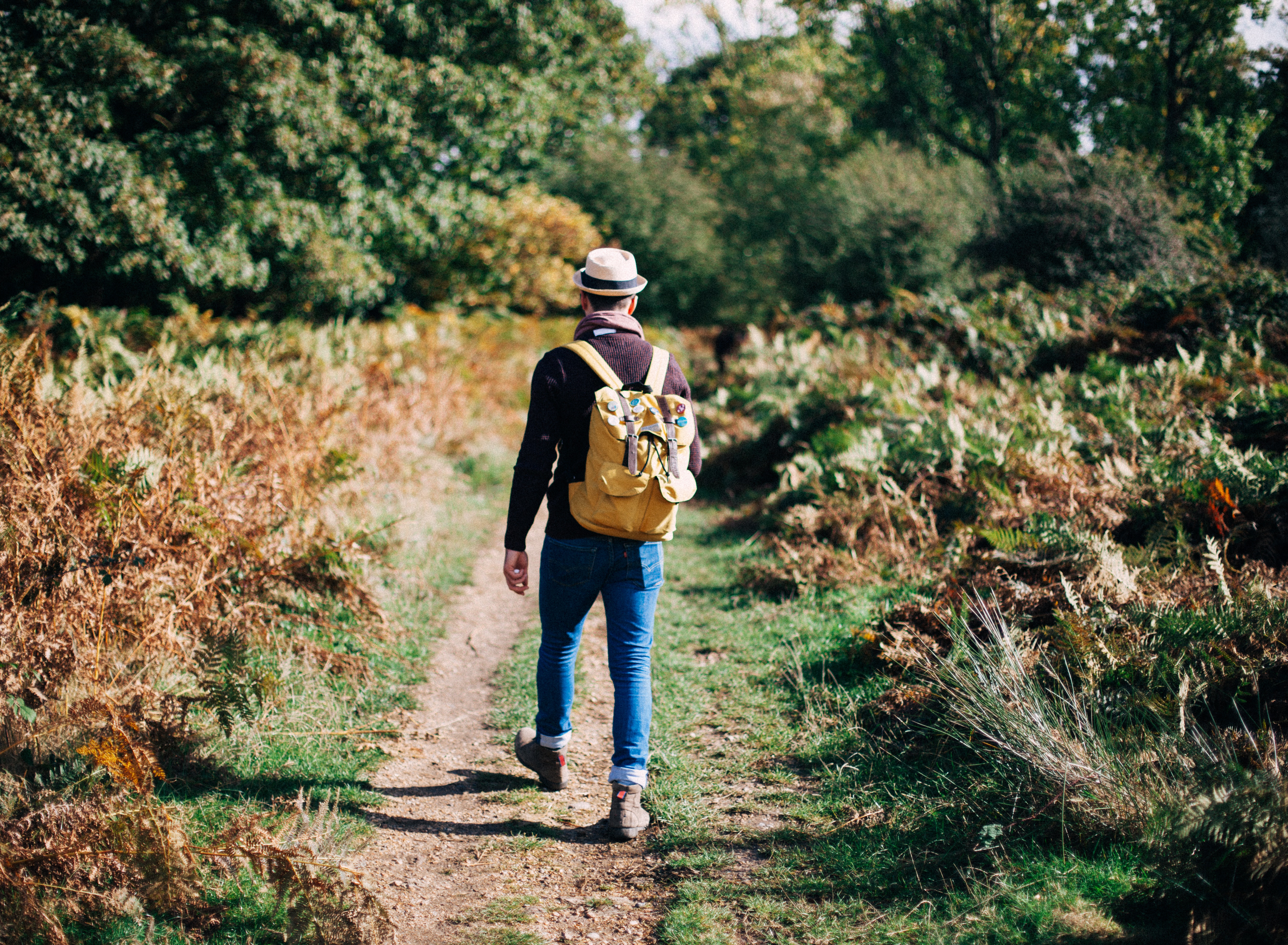 A man wearing a hat and rucksack walking in the countryside