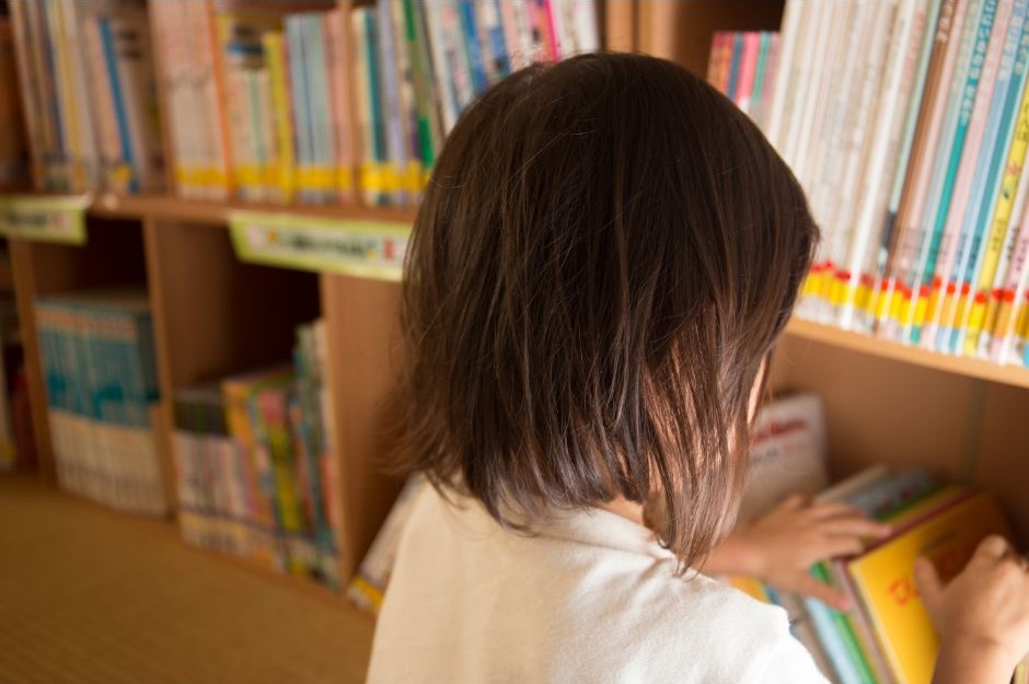 a child chooses books from library shelves