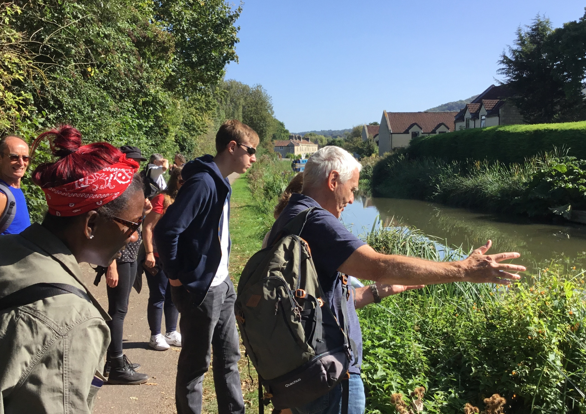 photo of a group of people on a riverside footpath with a guide pointing to the river
