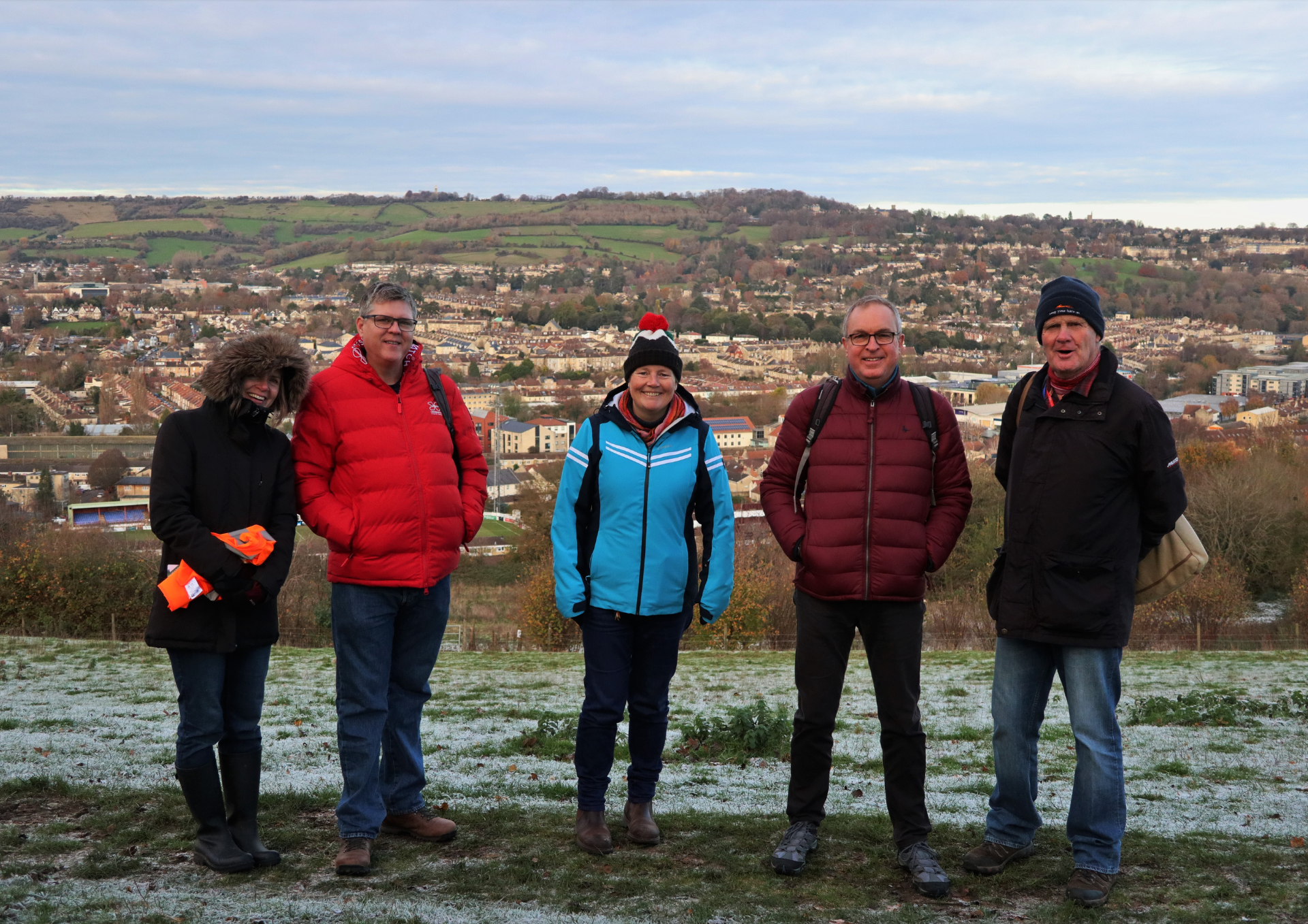 Five Bathscape walk leaders dressed in walking clothes with the skyline of Bath behind them
