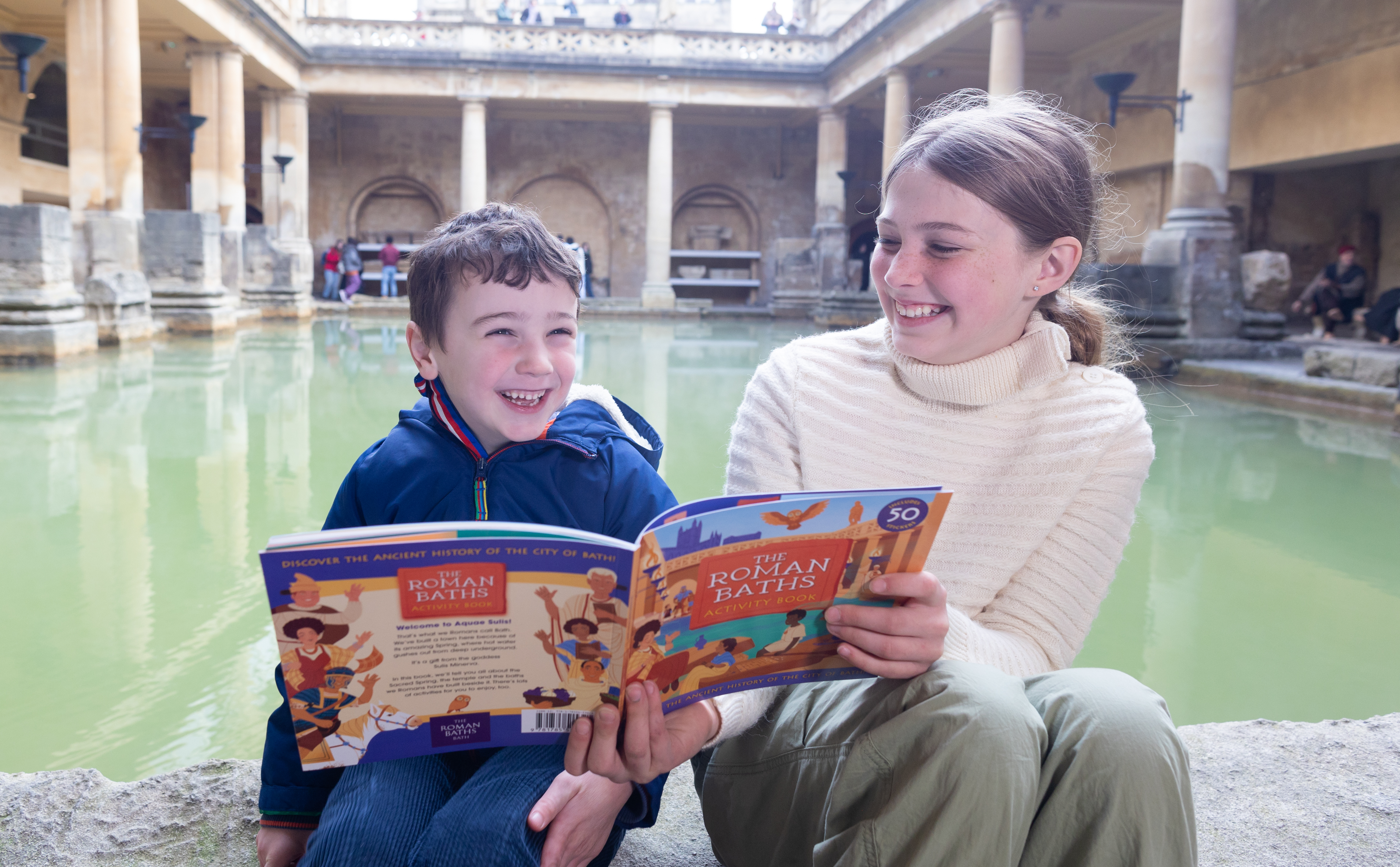 Boy and girl in front of the Great Bath at the Roman Baths, with the new Activity Guide