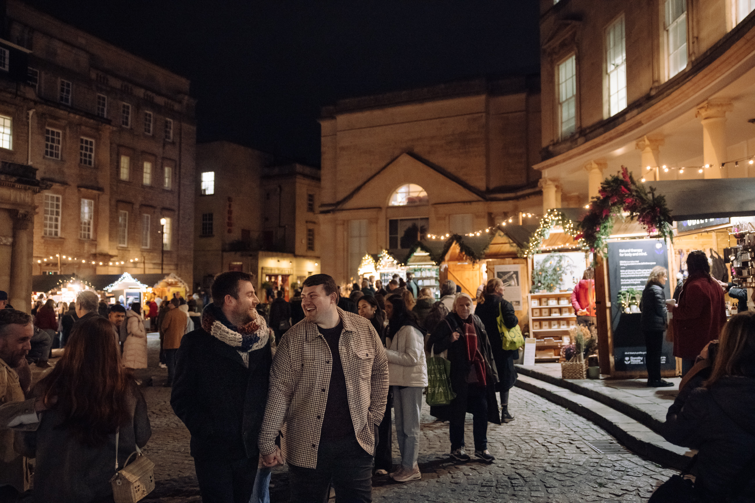 images shows a crowd among the Christmas market chalets at night