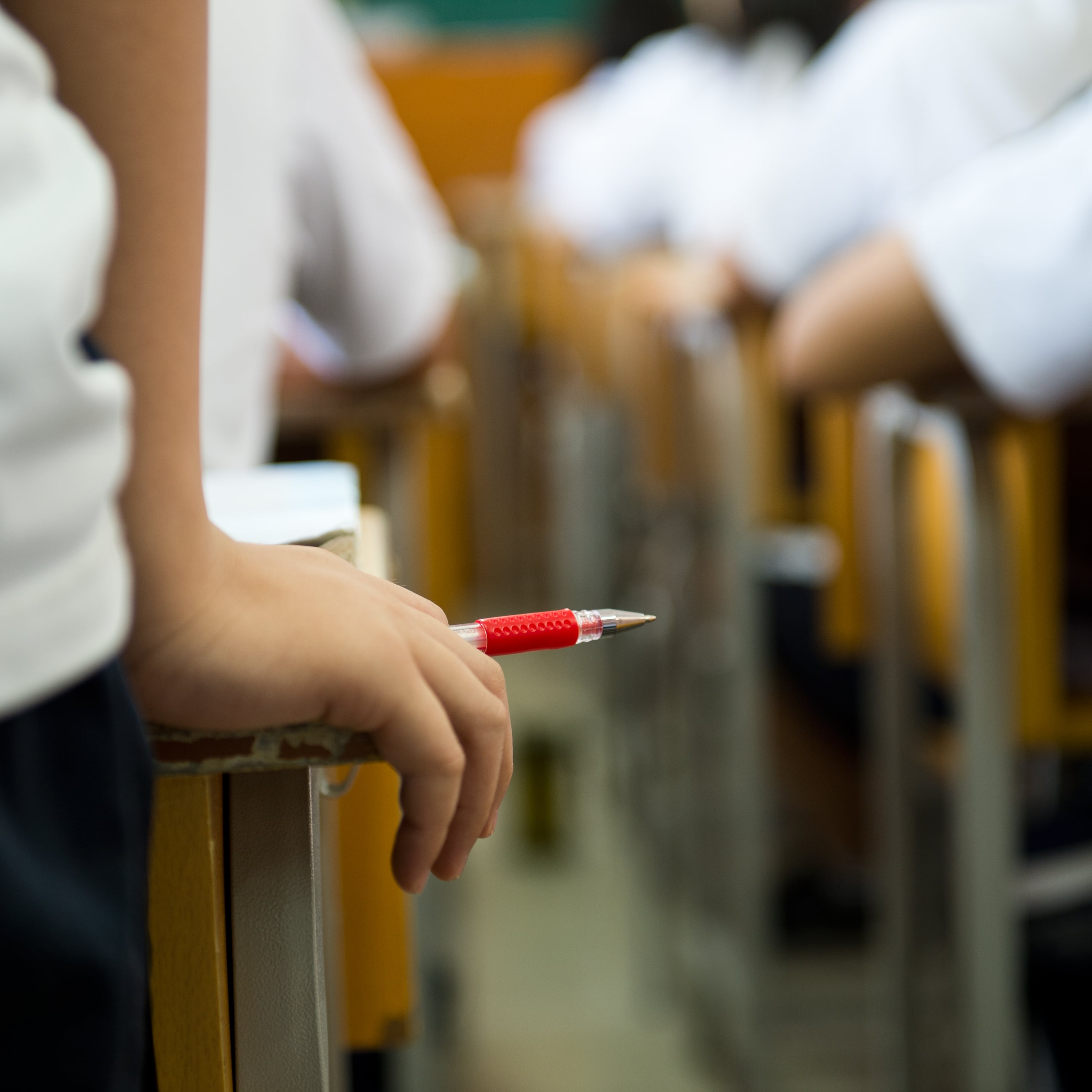 child holding pen in school