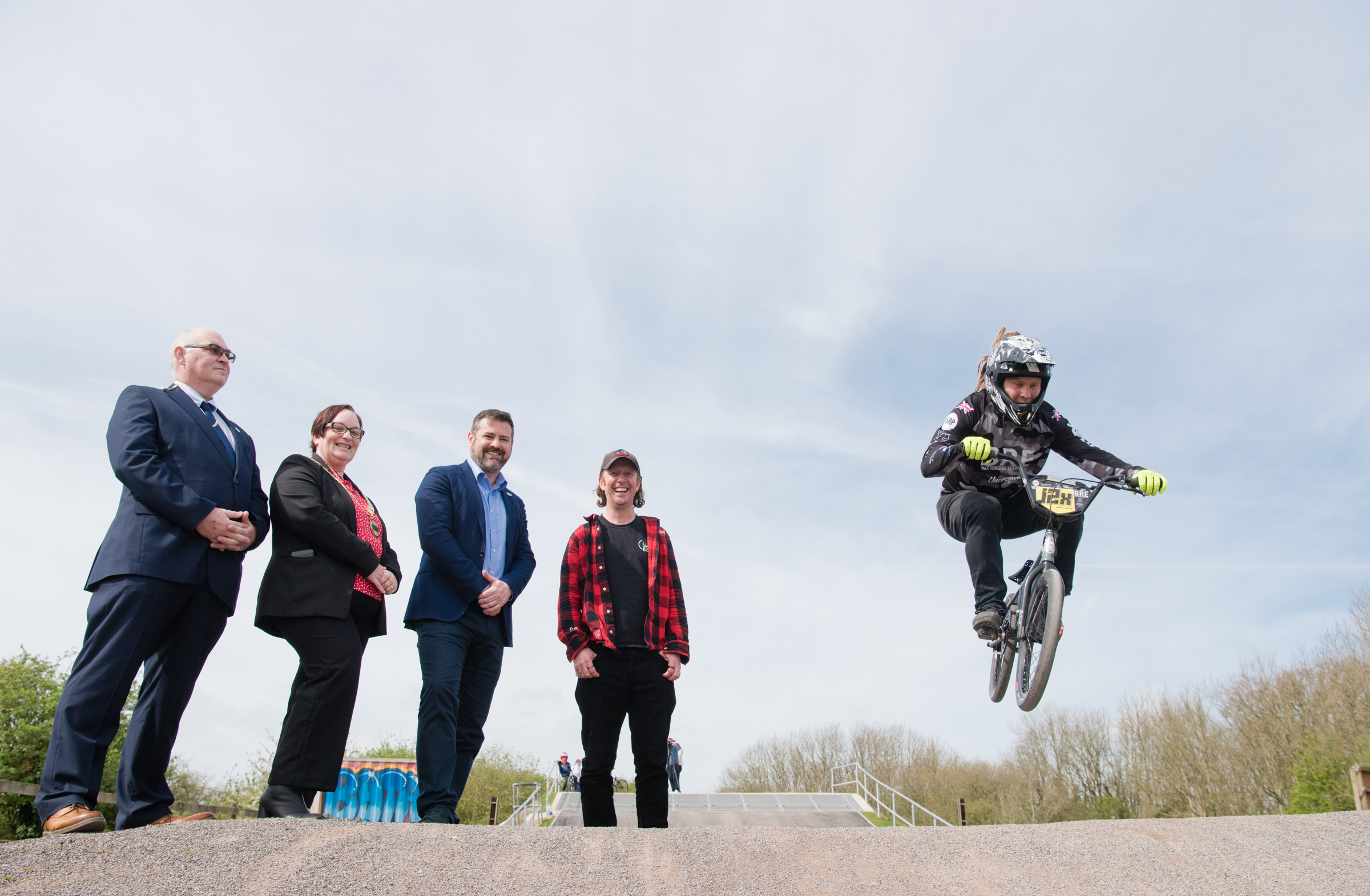 council and Bath BMX club staff stand and watch as BMX rider does a bike stunt off the ground