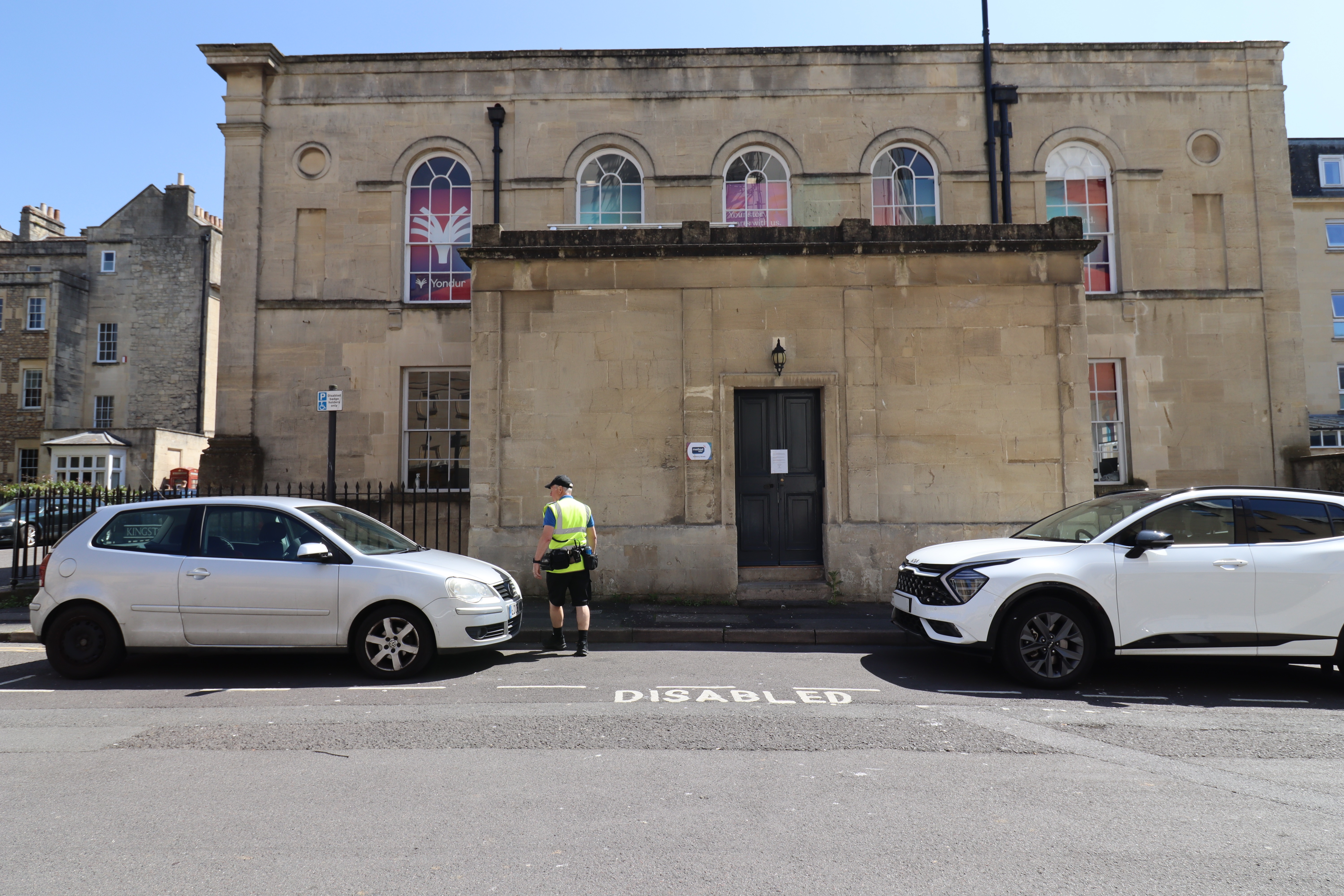 B&NES Civil Enforcement Officer walks between two parked vehicles. 