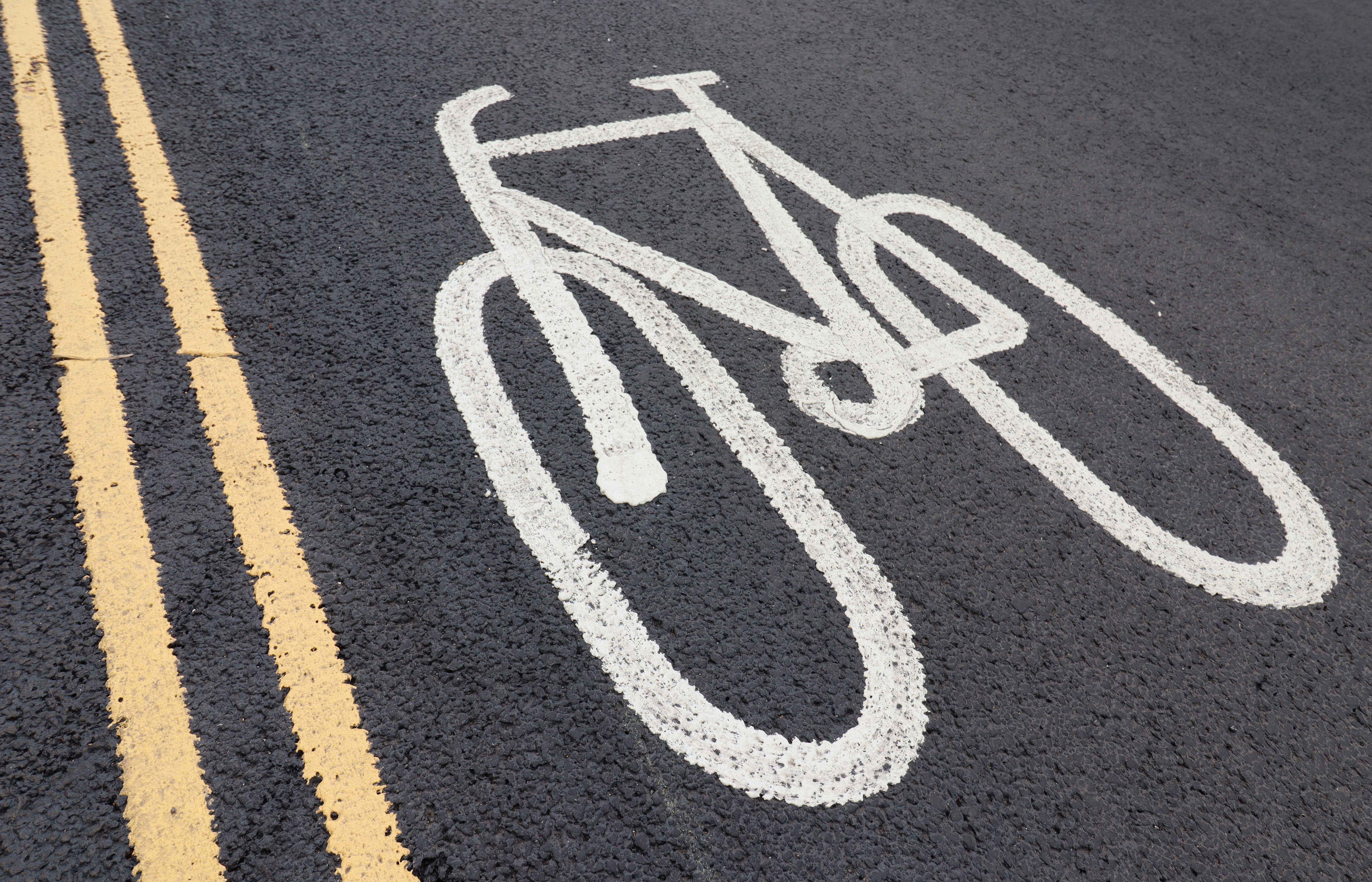 A cycle symble painted on a road next to double yellow lines. 