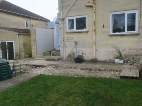 A house with an unfinished one-storey side extension. The outside wall has been built but there is no roof or front wall.