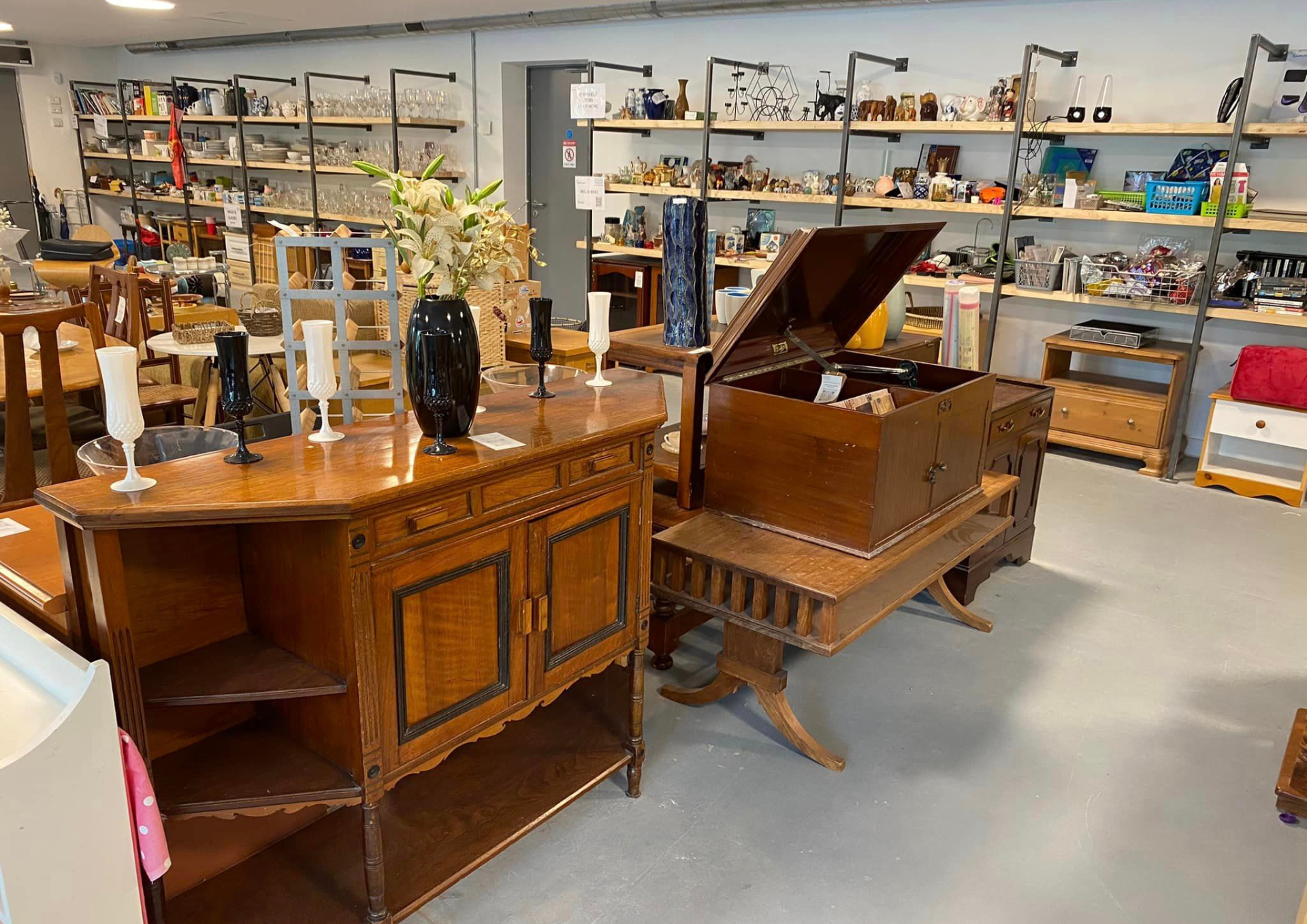 a photo of the inside of the reuse shop showing wooden furniture and shelves of household goods