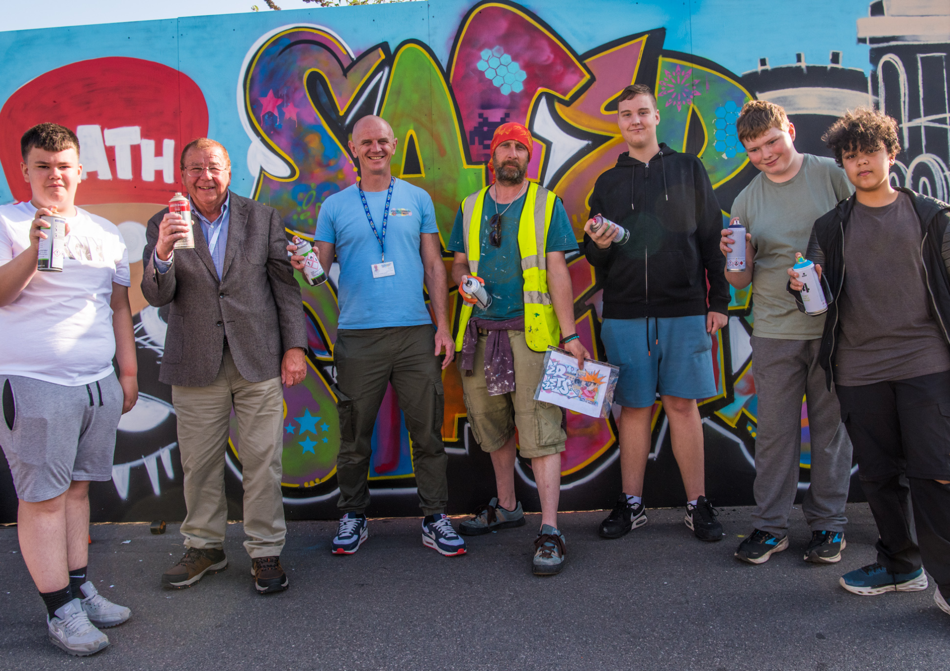 A photo of the wall and the young people who helped paint the artwork