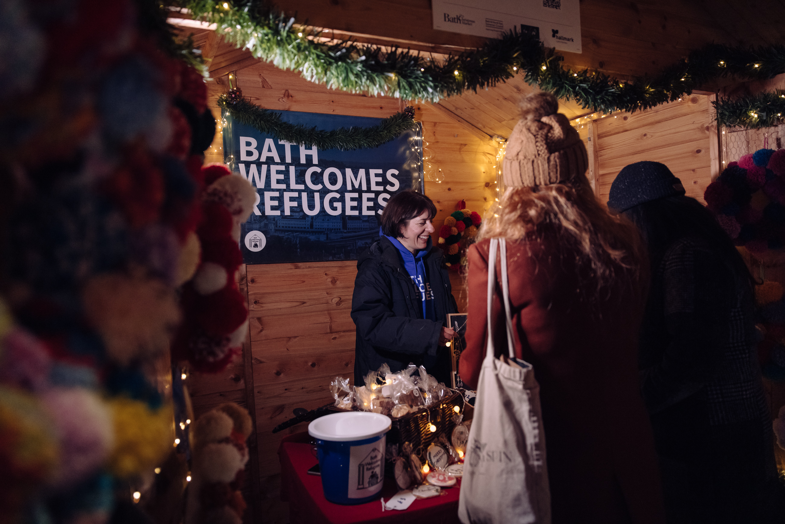 Charity employee serves a customer in a wooden chalet that has Christmas decorations