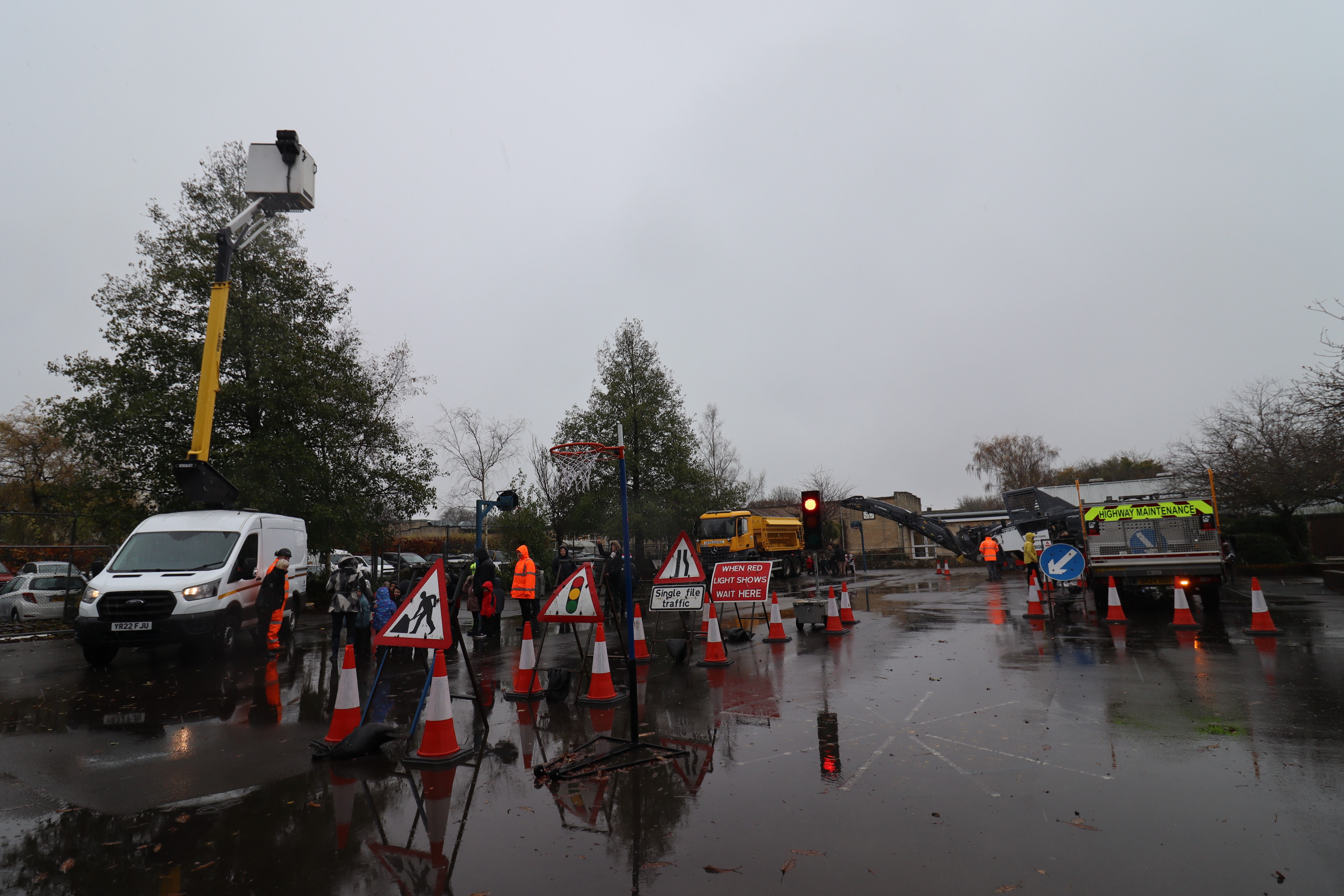 School children inspecting highway equipment in a playground. 