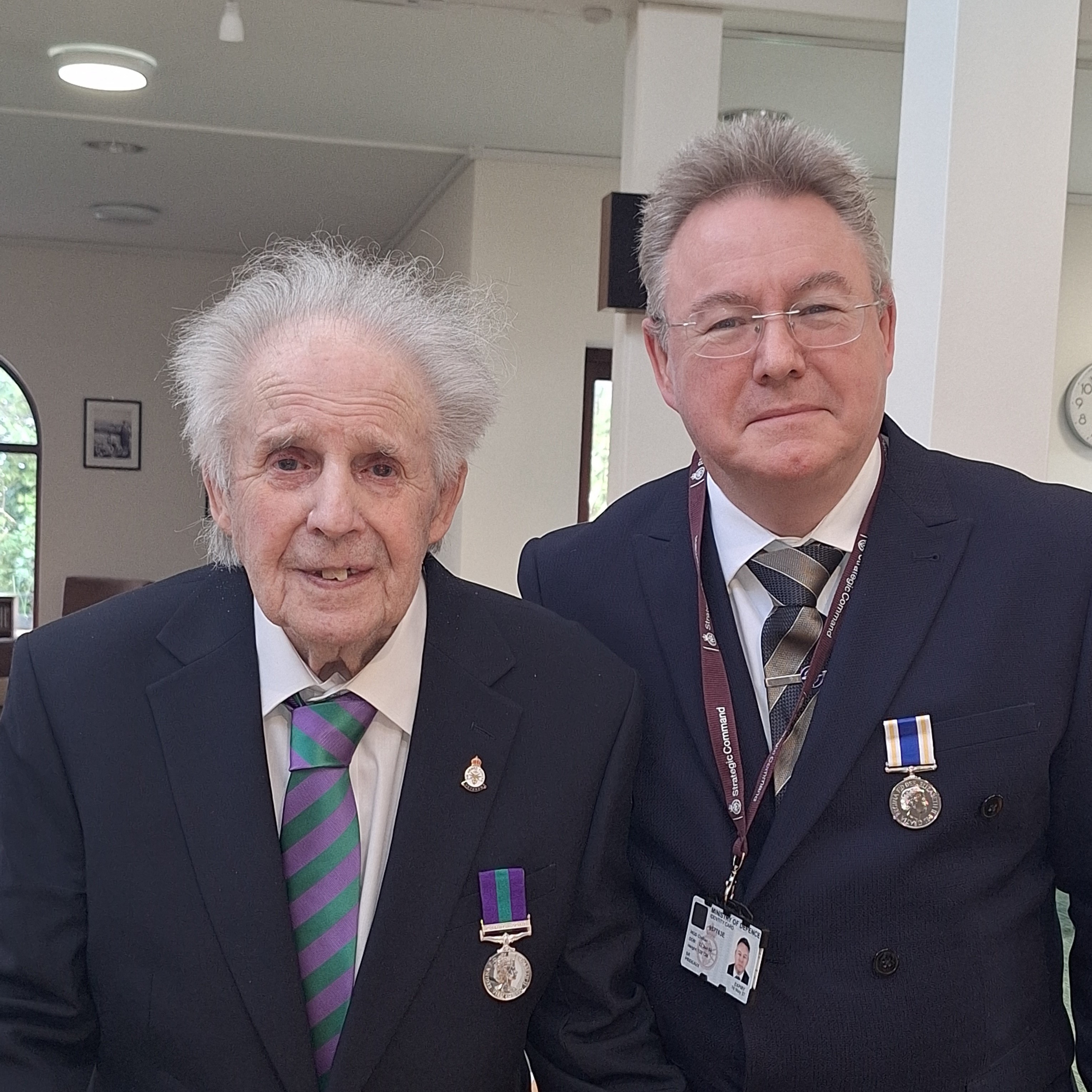 Two people wearing navy suits and war medals