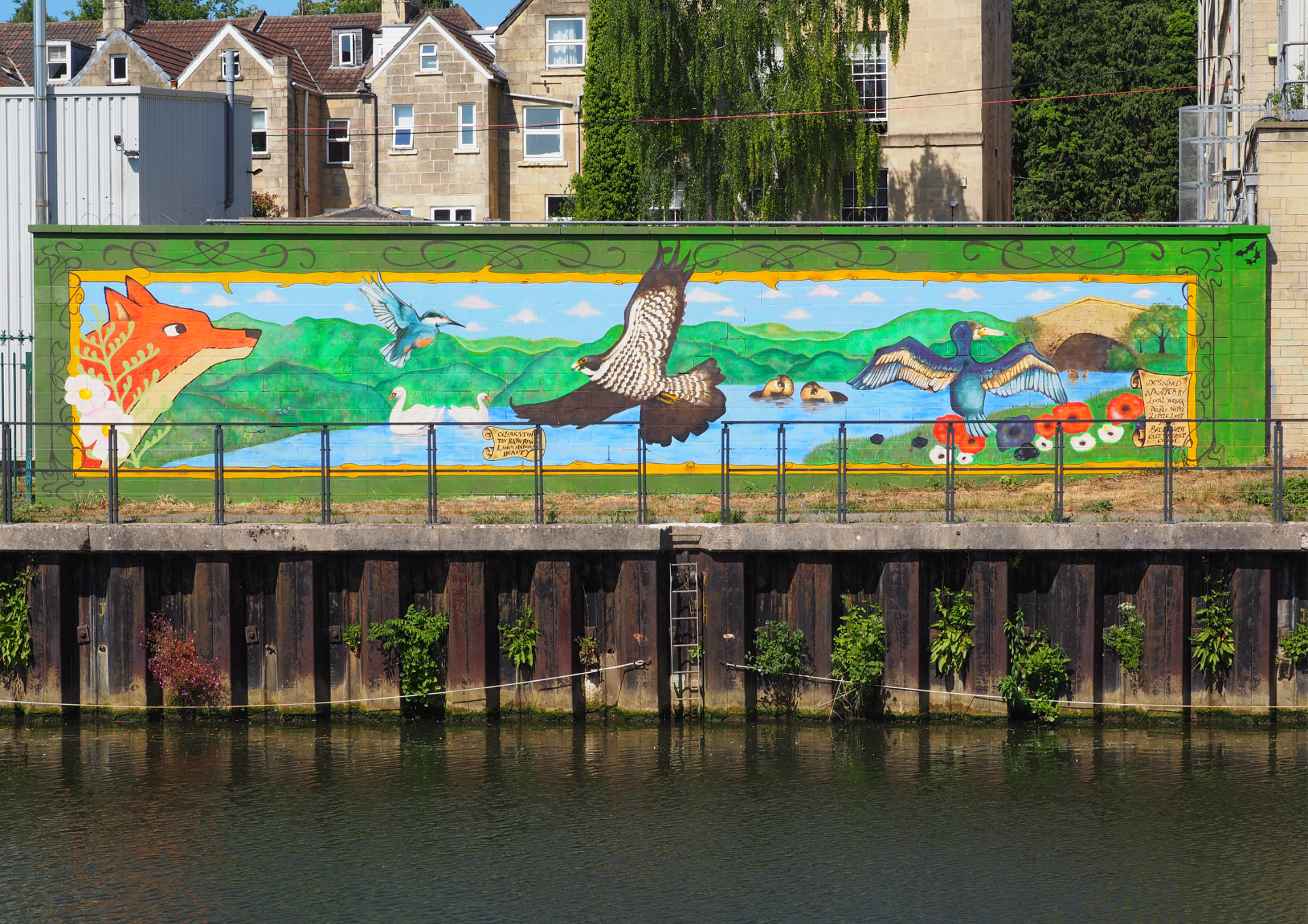 a photograph of the mural taken from the other side of the river. The image includes a river, a fox and several birds