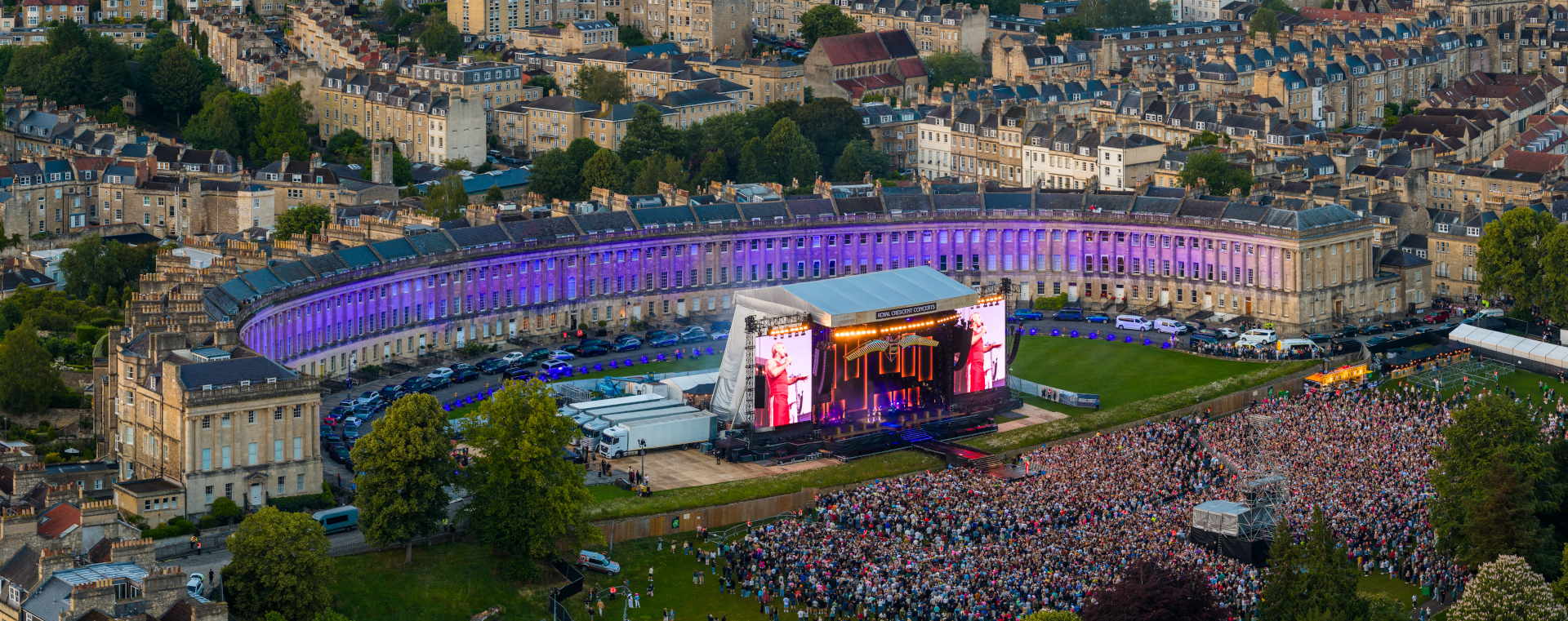 Drone photo of a lit stage in front of a crescent of georgian houses with the crowd in the foreground