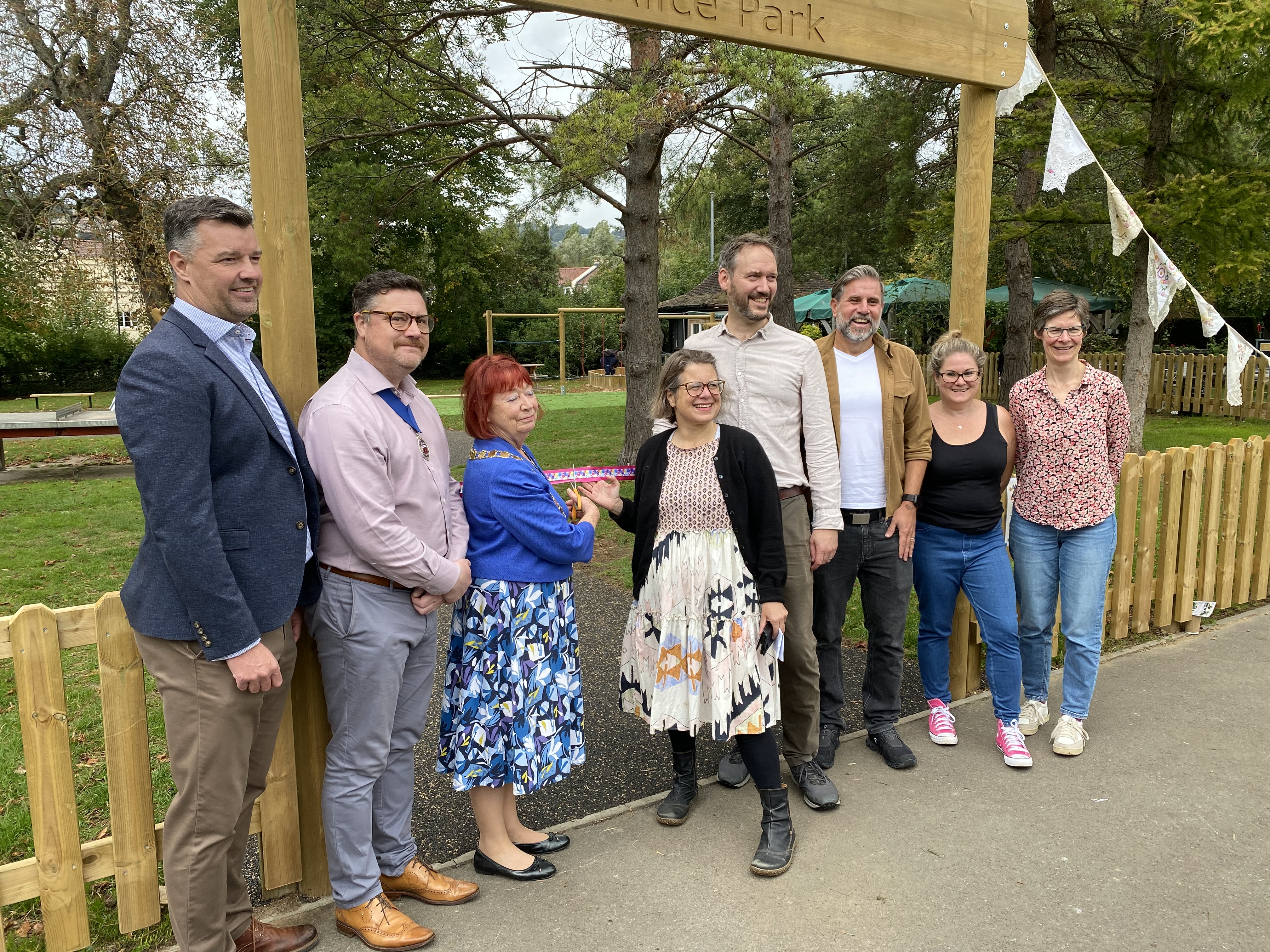 A group of people stand together to cut a ribbon at the entrance to Alice Park in Bath