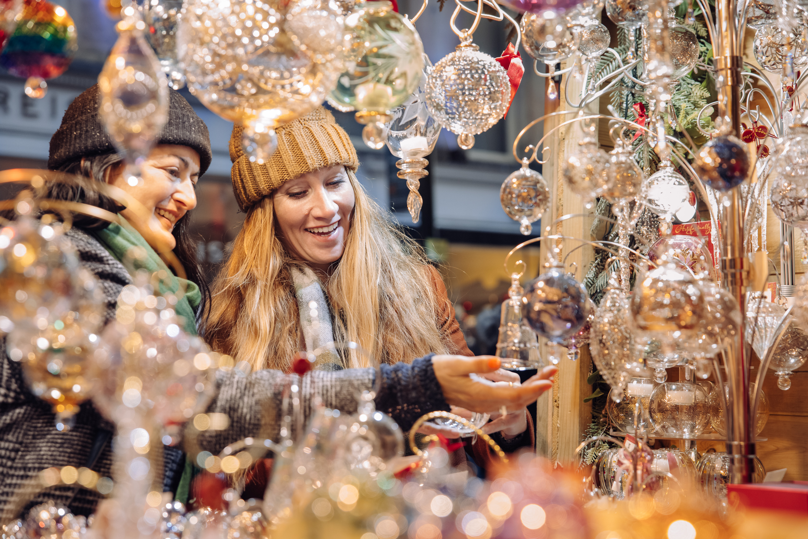 Two people smile as they look at Christmas decorations at a Christmas Market stall