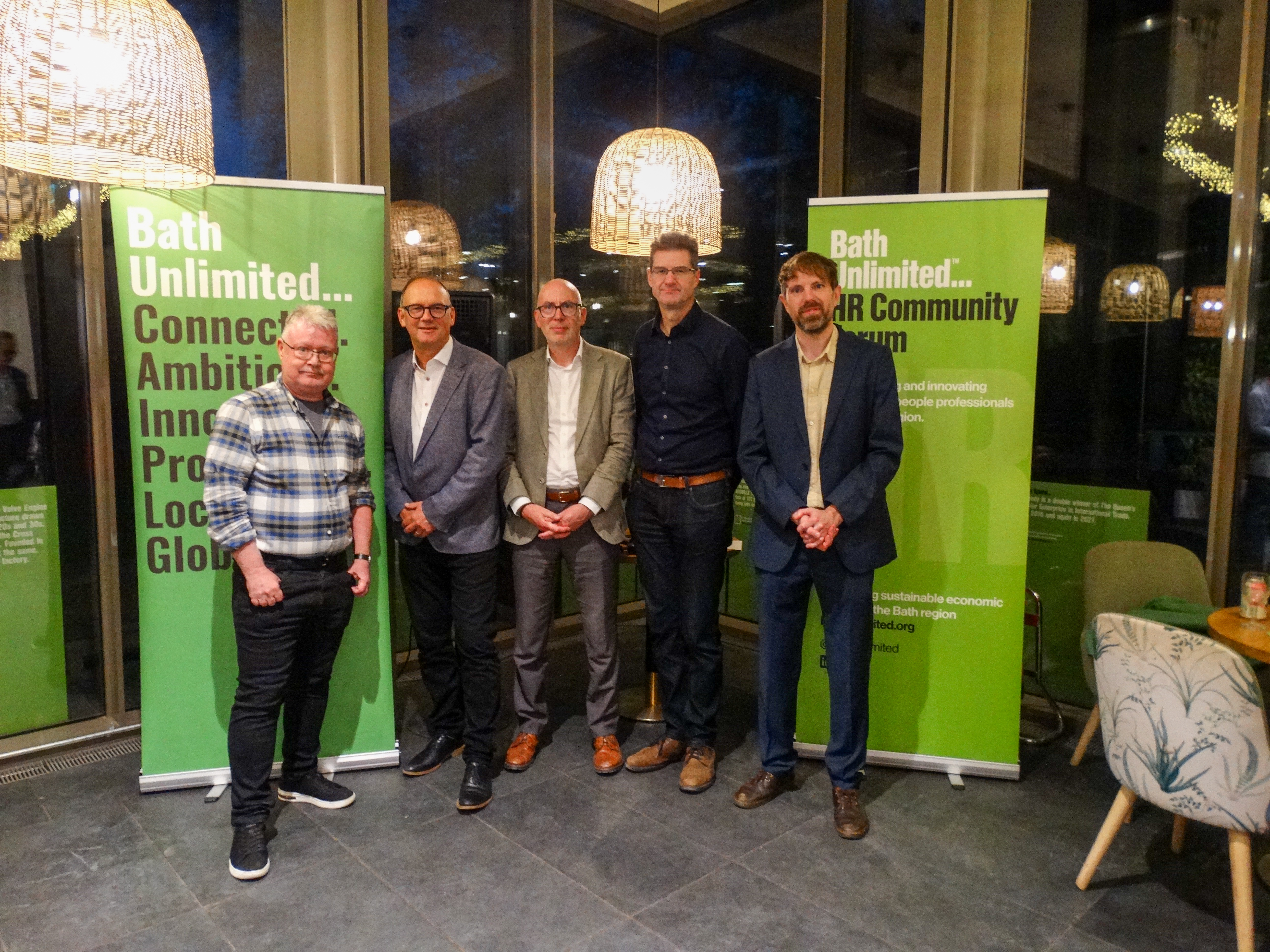 Five people stand by vertical green banners
