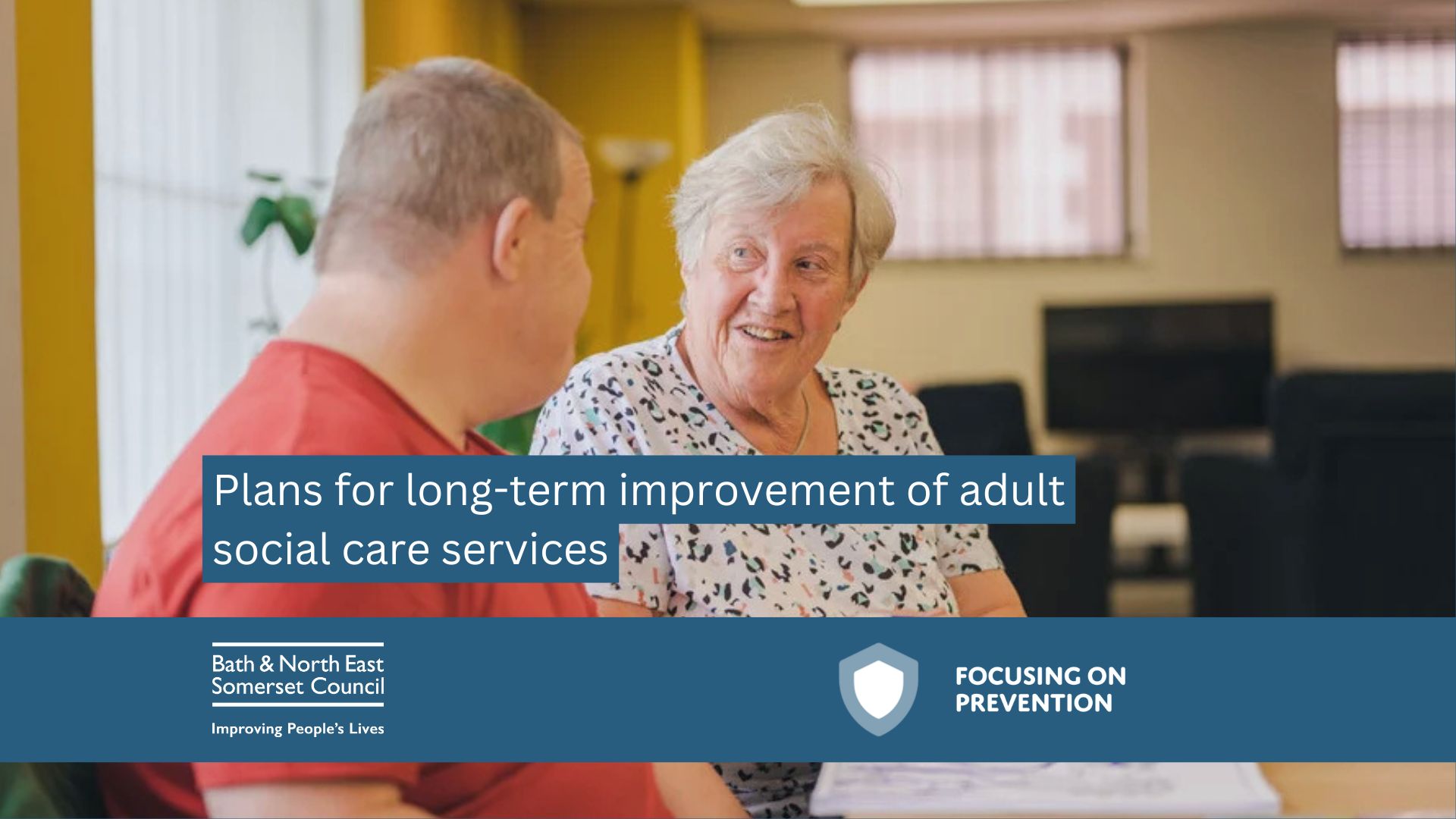 Carer sat at table talking to individual in a care setting