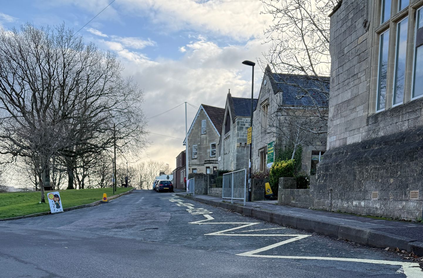 A school building alongside a road with yellow zigzag school markings