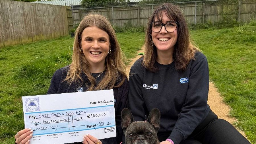 Bath Cats and Dogs Home representatives, with a small dog between them, hold up a cheque.