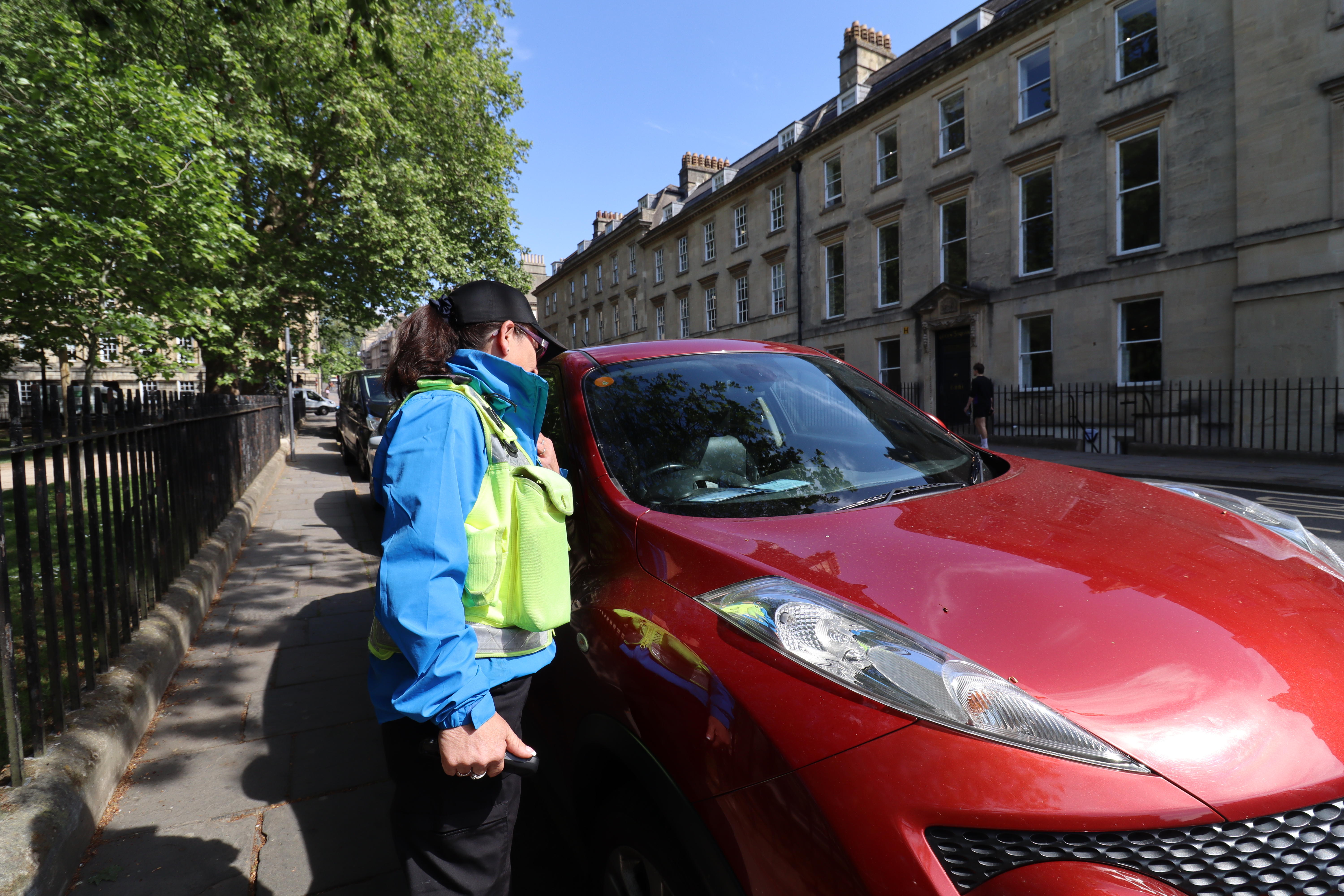 A Bath & North East Somerset Council Civil Enforcement Officer checking a Blue Badge in Queen Square, Bath. 