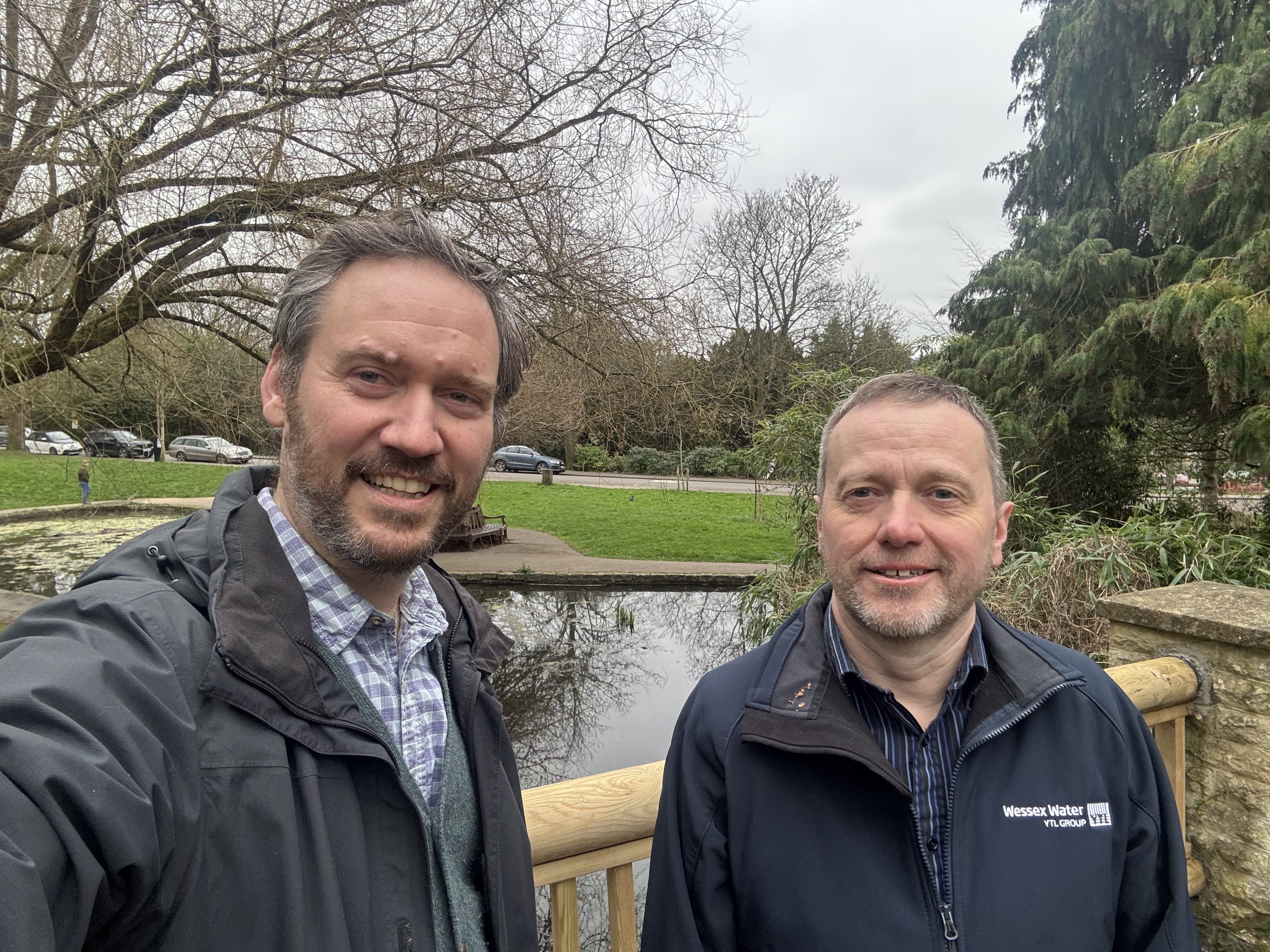 two men stand by a pond