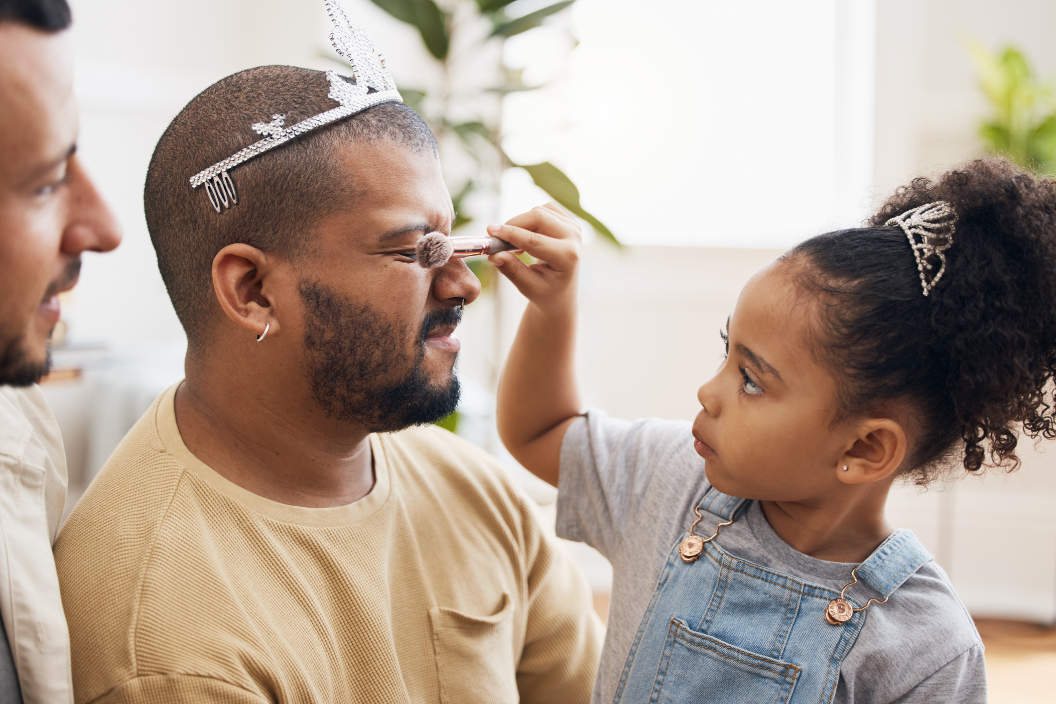 A child puts make up on a foster parent, he wears a tiara