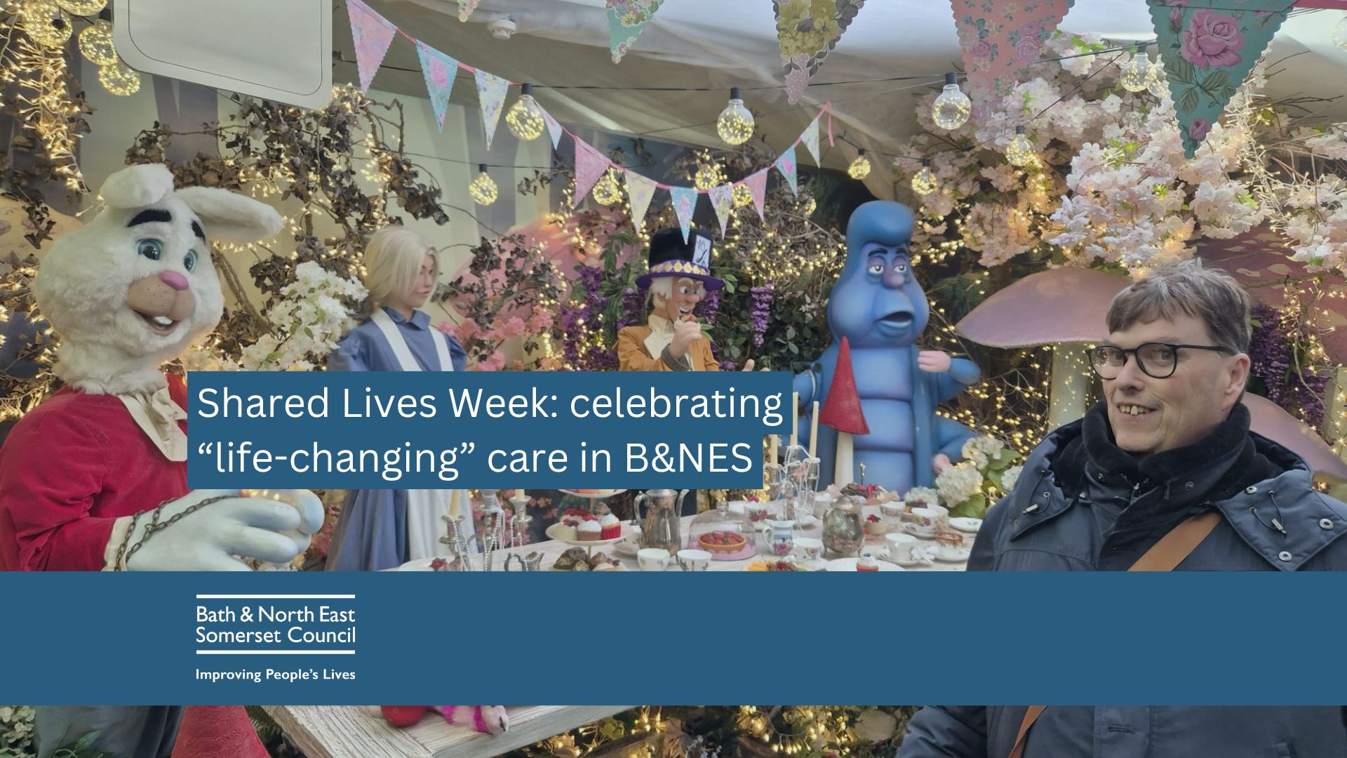 Shared Lives user R stands in front of an Alice in Wonderland themed display at Lacock Abbey National Trust, with support from Carer, Sue