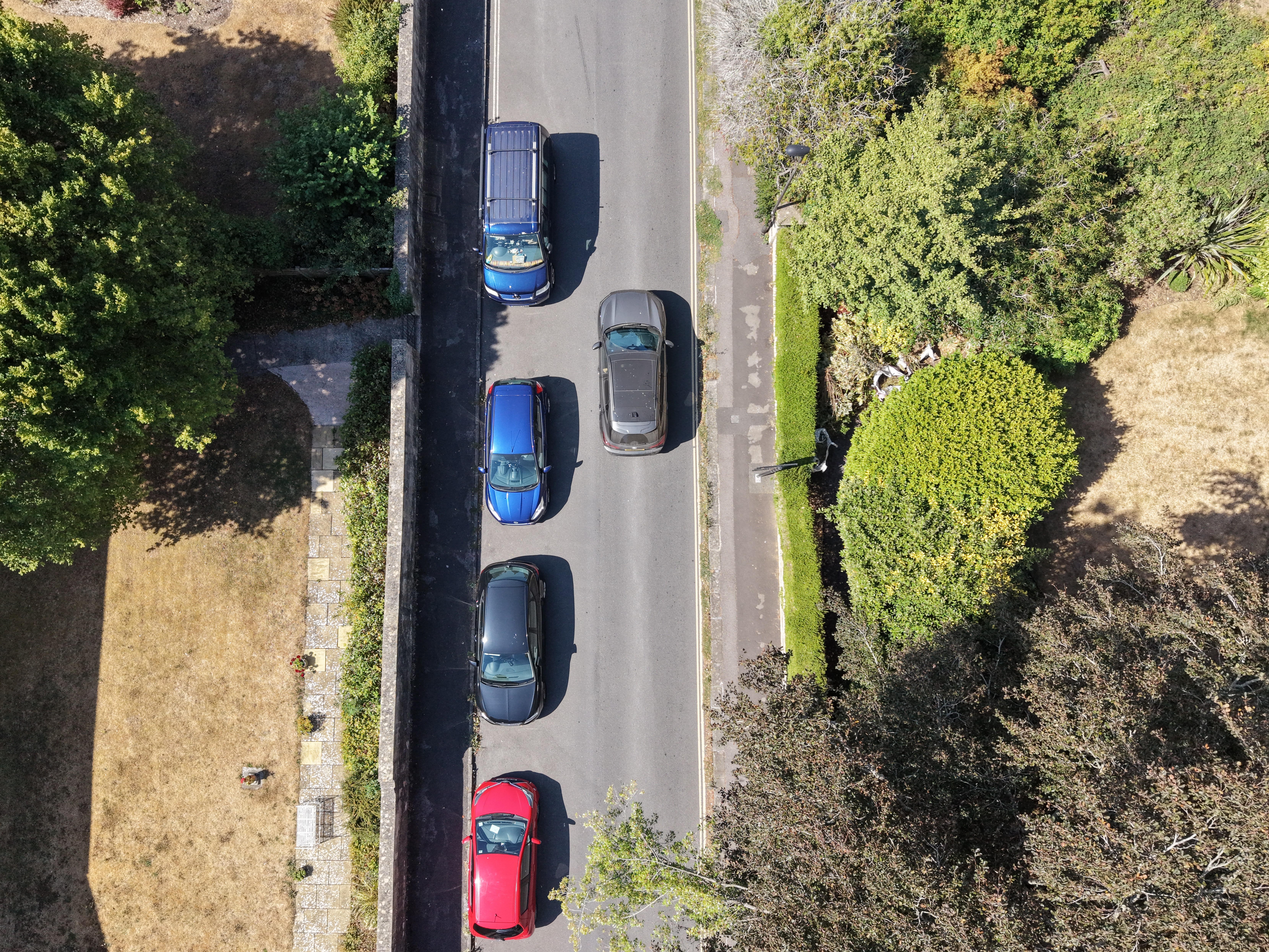 An image showing cars of different sizes parked on the road. 