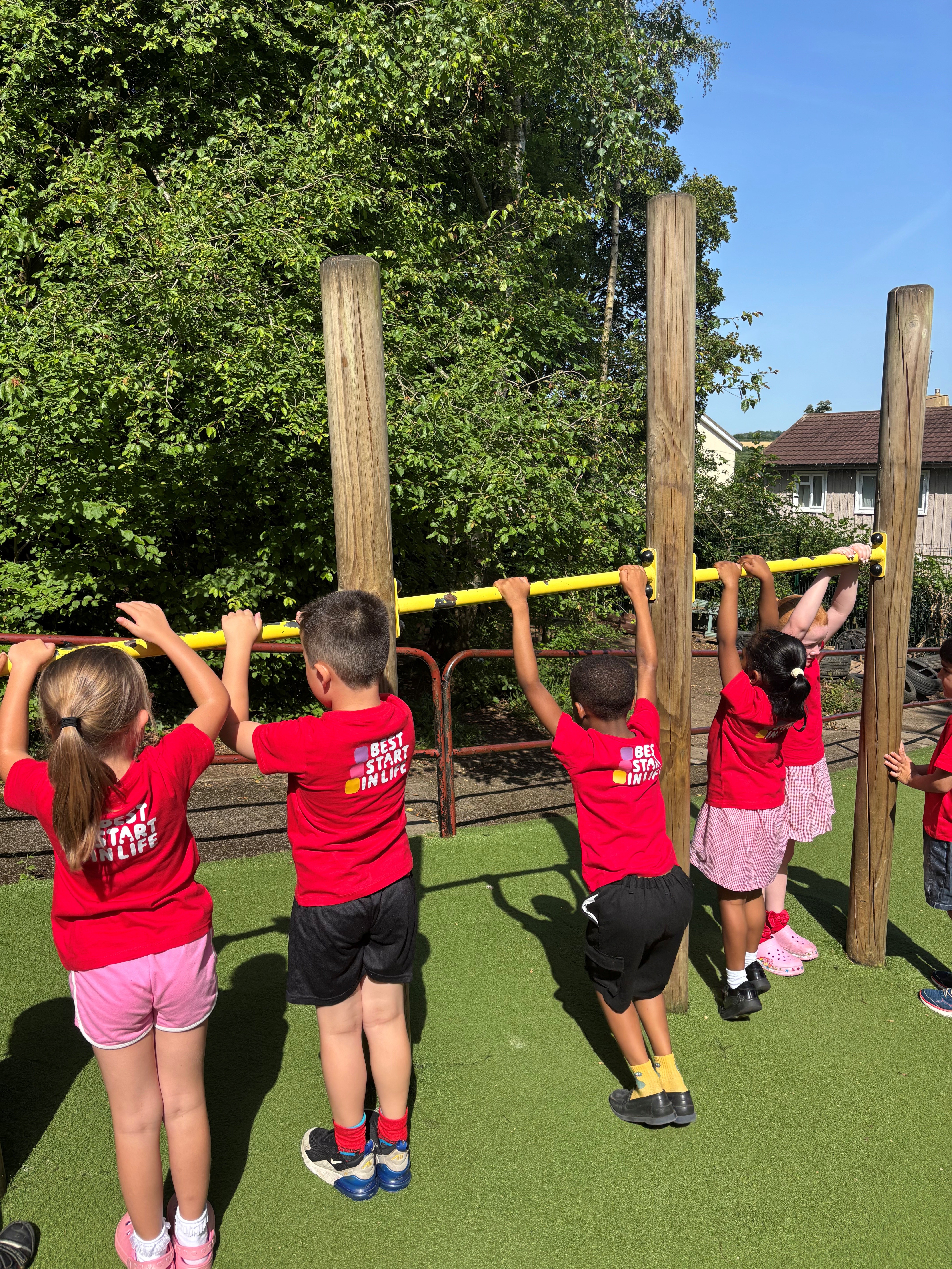 Young children in red t-shirts playing in a park
