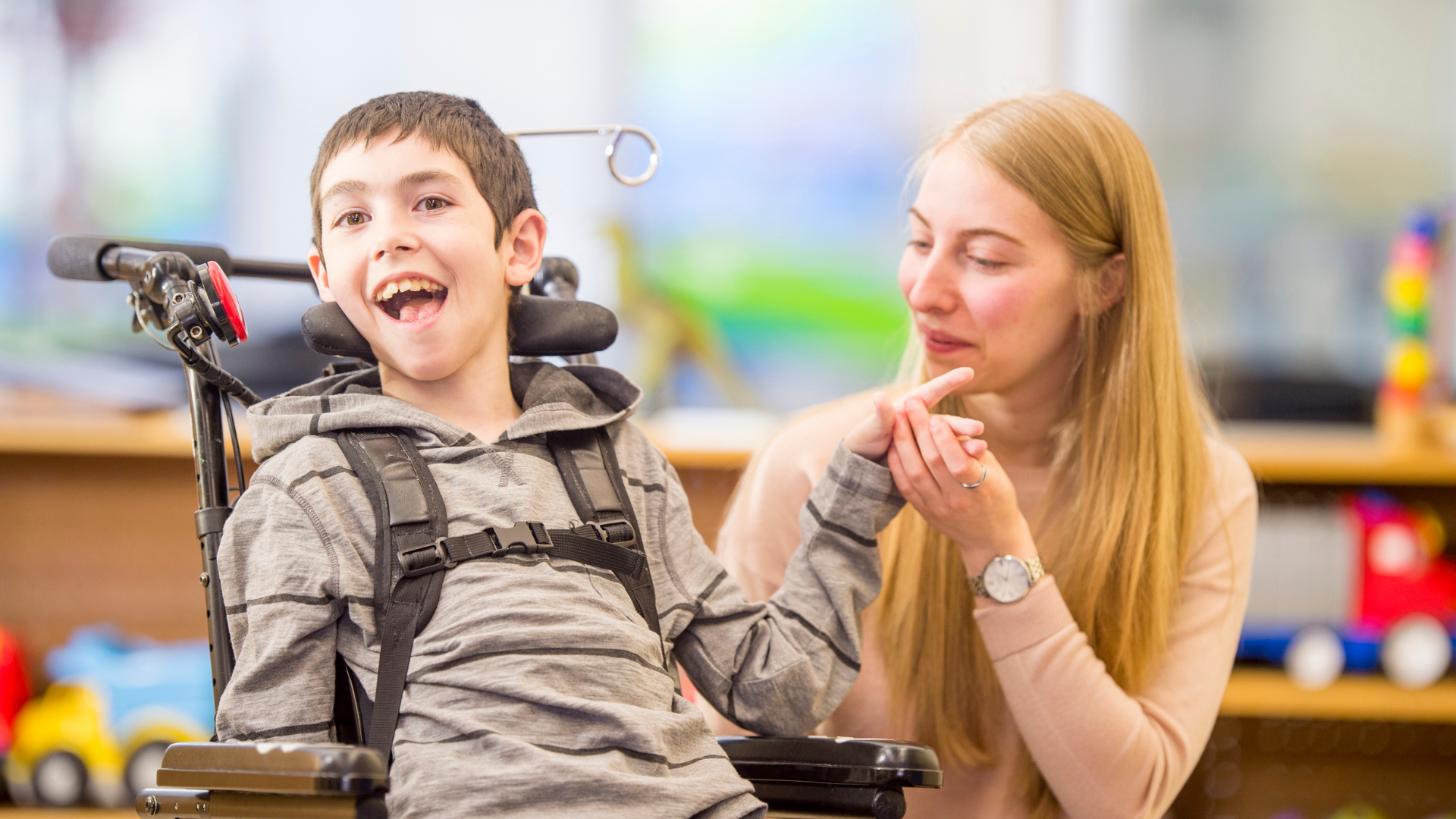 image shows a young boy with special educational needs and a female carer smiling