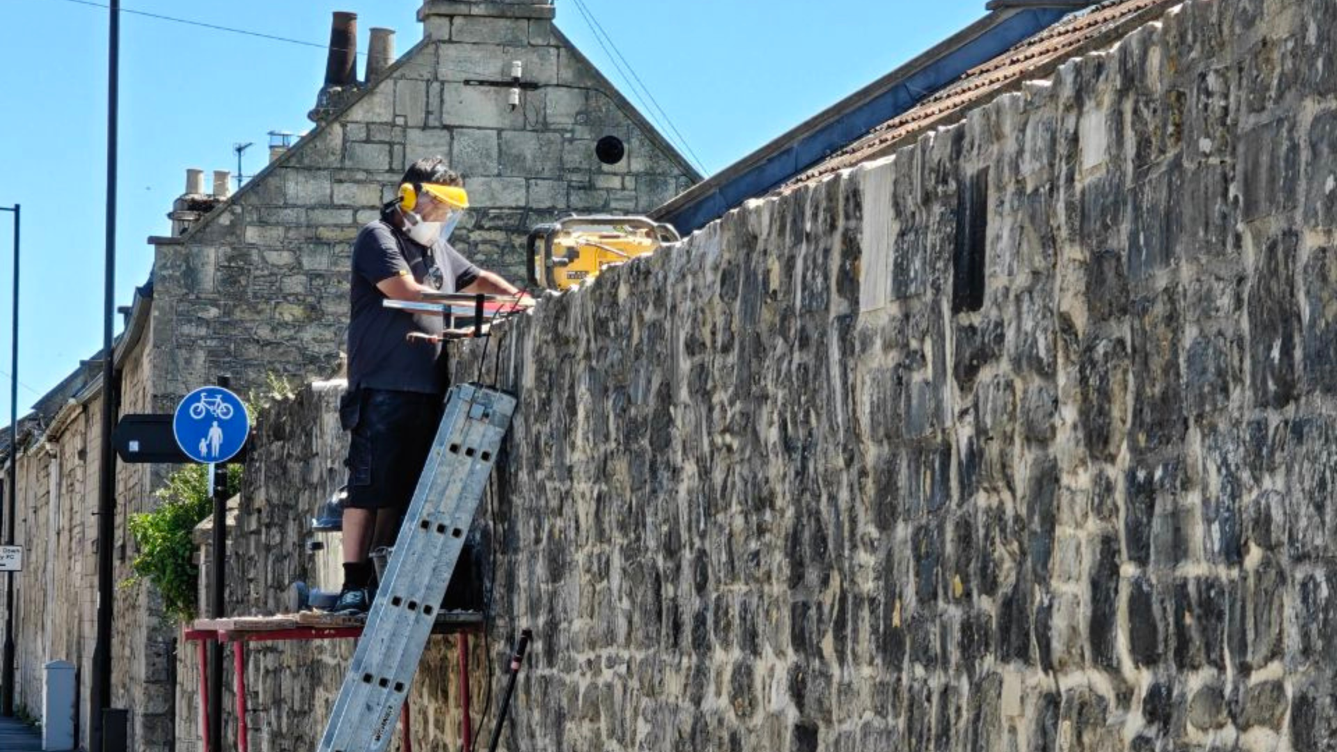 A mason on a ladder works on a burial site.