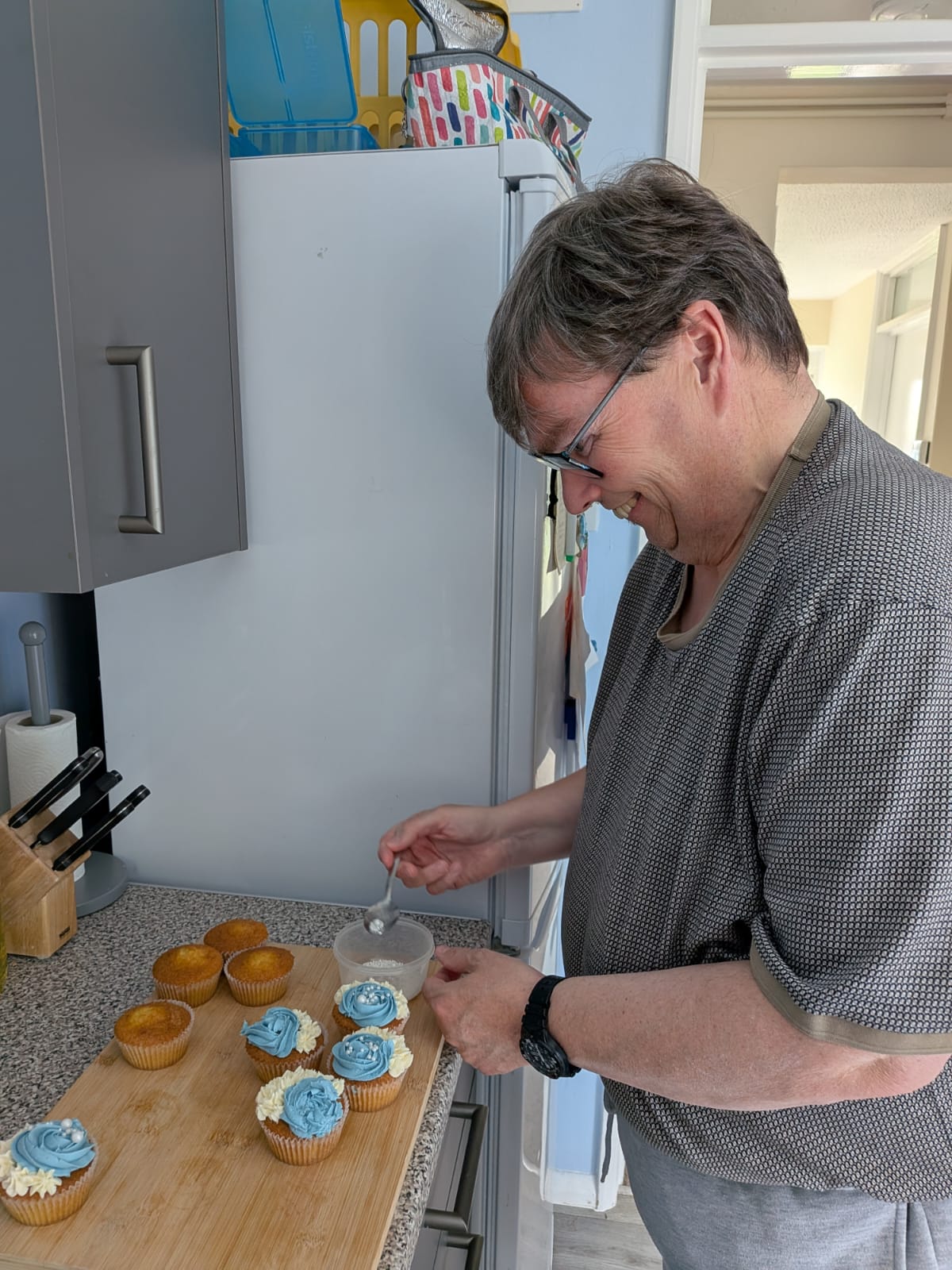Shared Lives user, R, decorates cakes in their kitchen, with support from carer, Sue