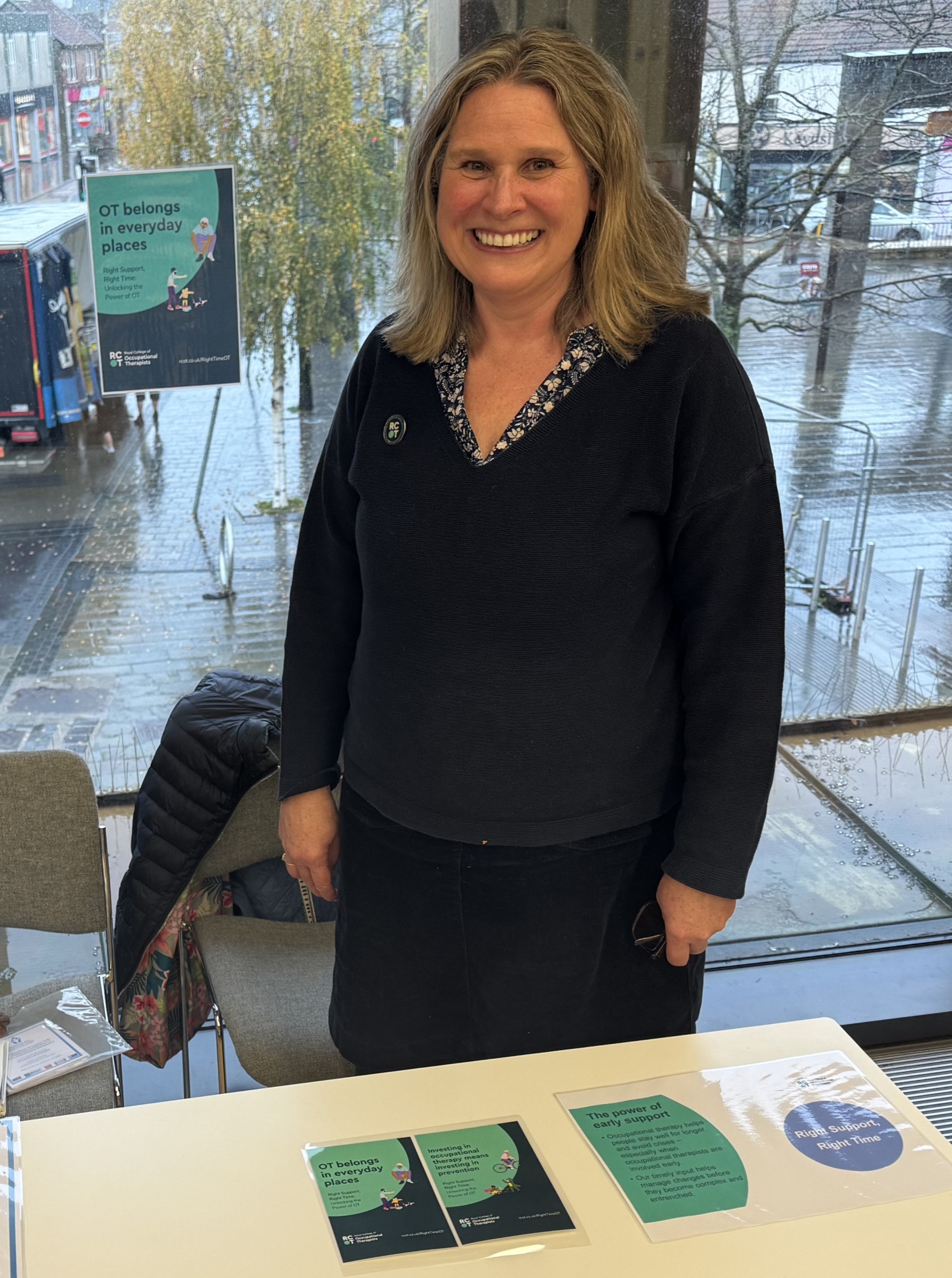 Esme Neale, who runs Enabling You OT support, standing at their table at the Community Catalyst event.